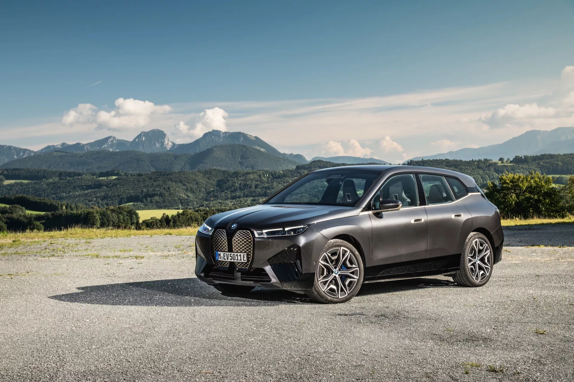 SUV de lujo BMW iX (i20) del 2021 aparcado al aire libre mostrando su diseño moderno con un fondo montañoso pintoresco, destacando la parrilla frontal, los faros LED y el cuerpo aerodinámico elegante