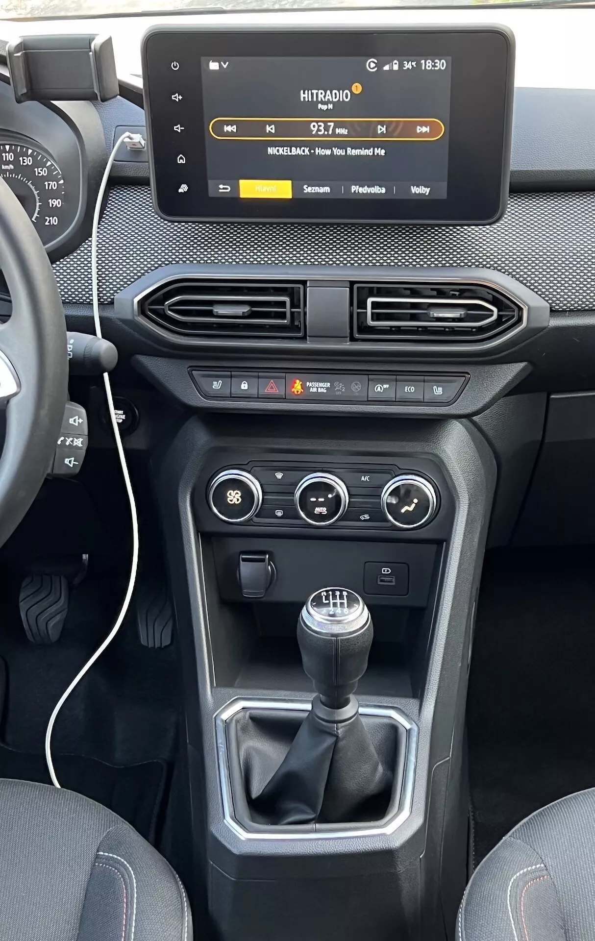 Vista interior del Dacia Jogger 2022 centrada en la consola central y el tablero, destacando una pantalla táctil flotante de infotenimiento, rejillas de aire, controles de clima y vehículo, y un cambio de marchas manual