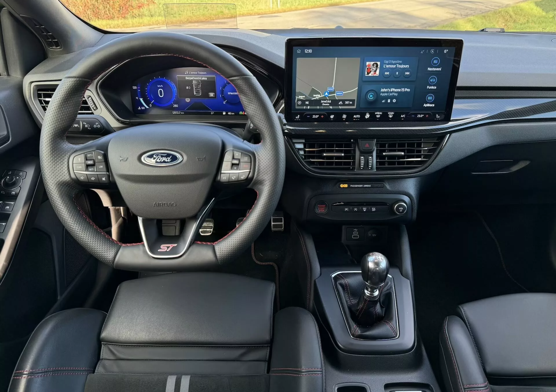 Interior del Ford Focus ST 2022 desde la perspectiva del conductor mostrando el volante multifunción de cuero con marca ST, cuadro de instrumentos digital, sistema de infoentretenimiento táctil, transmisión manual y asientos de cuero.