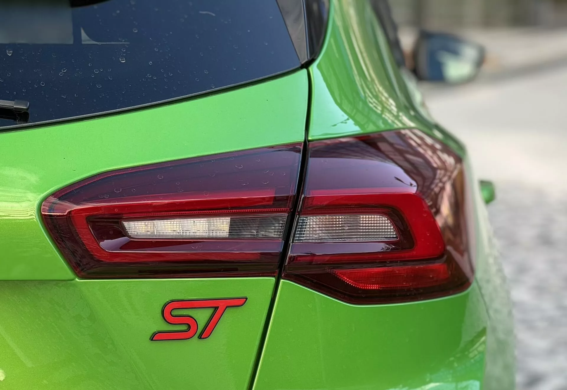 Vista detallada de la parte trasera del Ford Focus ST 2022 con luz trasera LED y pintura verde resaltando la insignia deportiva ST y la tecnología de iluminación avanzada