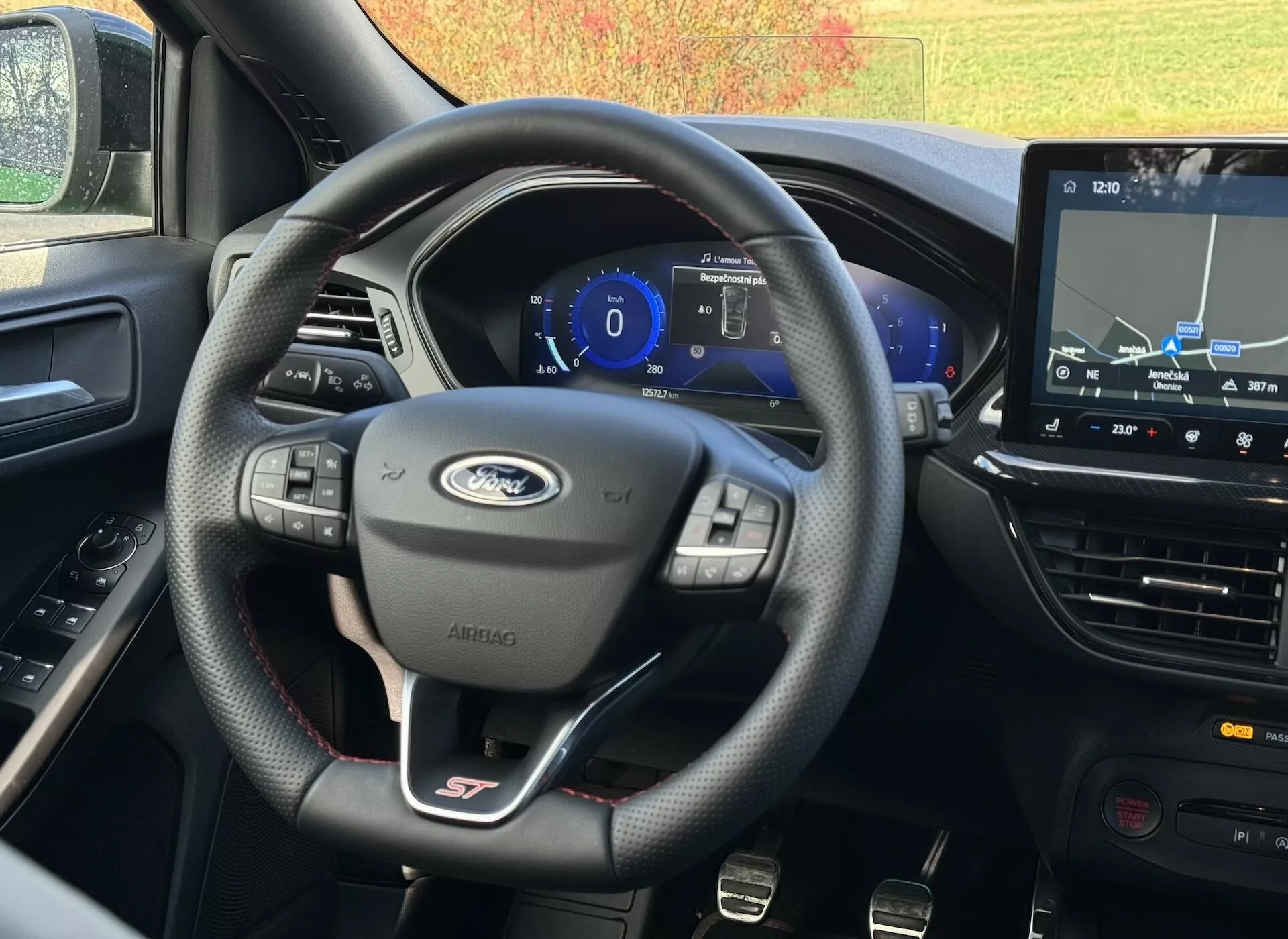 Vista interior del Ford Focus ST 2022 desde el asiento del conductor mostrando volante de cuero con insignia ST, cuadro de instrumentos digital y sistema de navegación táctil