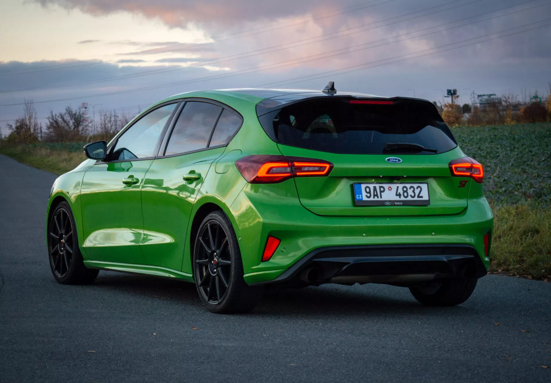 Ford Focus ST 2022 en verde vibrante con diseño deportivo, vista trasera tres cuartos mostrando luces traseras, ruedas y escape doble