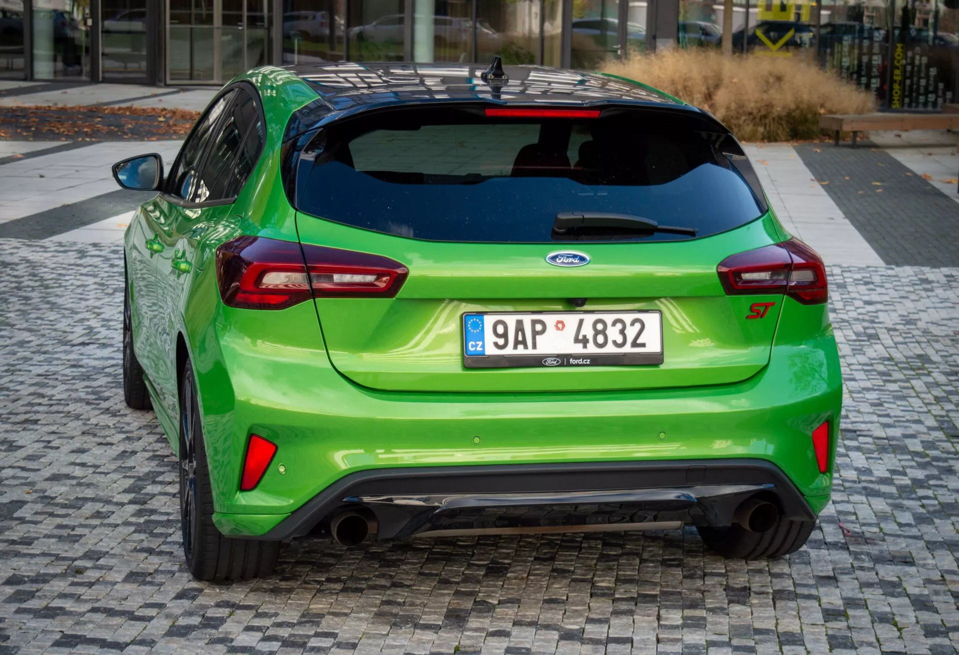 Ford Focus ST 2022 en verde brillante, mostrando su ángulo trasero deportivo con escape doble, alerón trasero y luces traseras LED