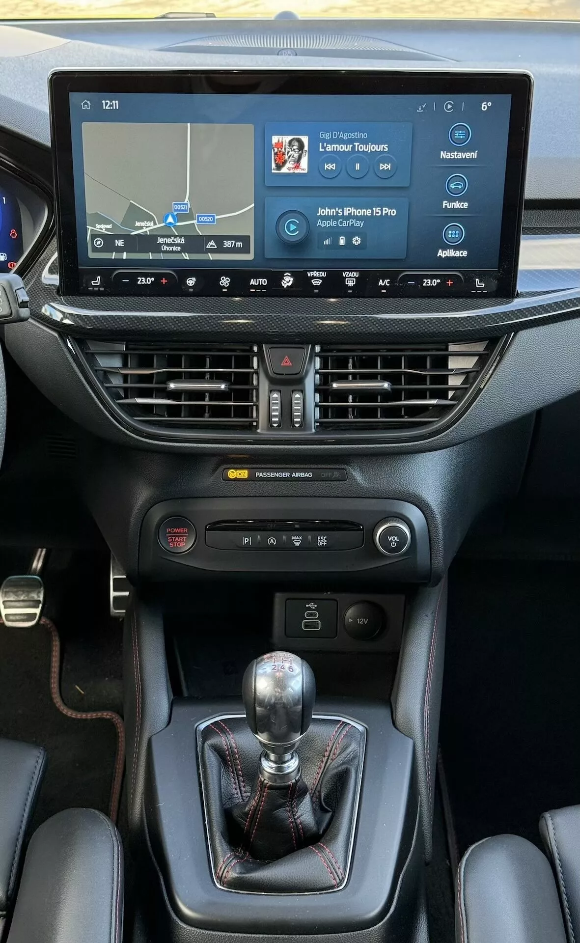 Interior del Ford Focus ST 2022 destacando la consola central con pantalla táctil de infotenimiento que muestra navegación y conectividad, control climático de doble zona, palanca de cambios manual, controles de dinámica del vehículo y portavasos, enfatizando la tecnología y los detalles de diseño premium.