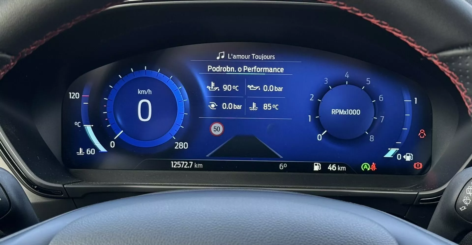 Vista cercana del tablero digital del Ford Focus ST 2022 mostrando velocímetro, tacómetro, temperatura exterior, presión del turbo y temperatura del refrigerante con costura roja deportiva en el borde del volante