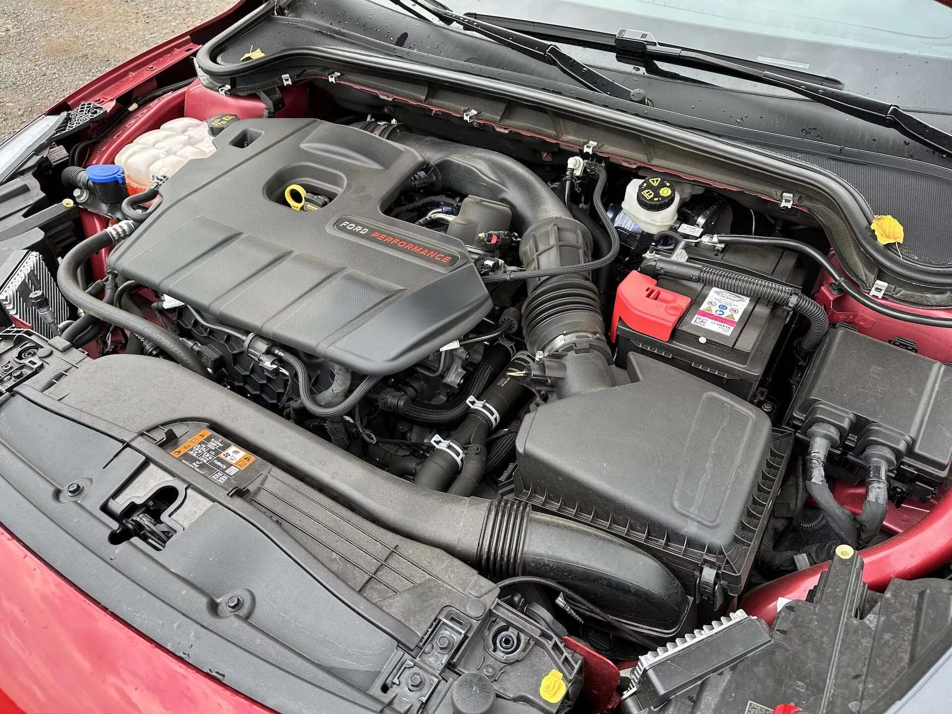 Vista cercana del compartimiento del motor del Ford Focus 2022 mostrando el bloque del motor, el sistema de admisión de aire, la batería y los depósitos de líquido desde un ángulo elevado