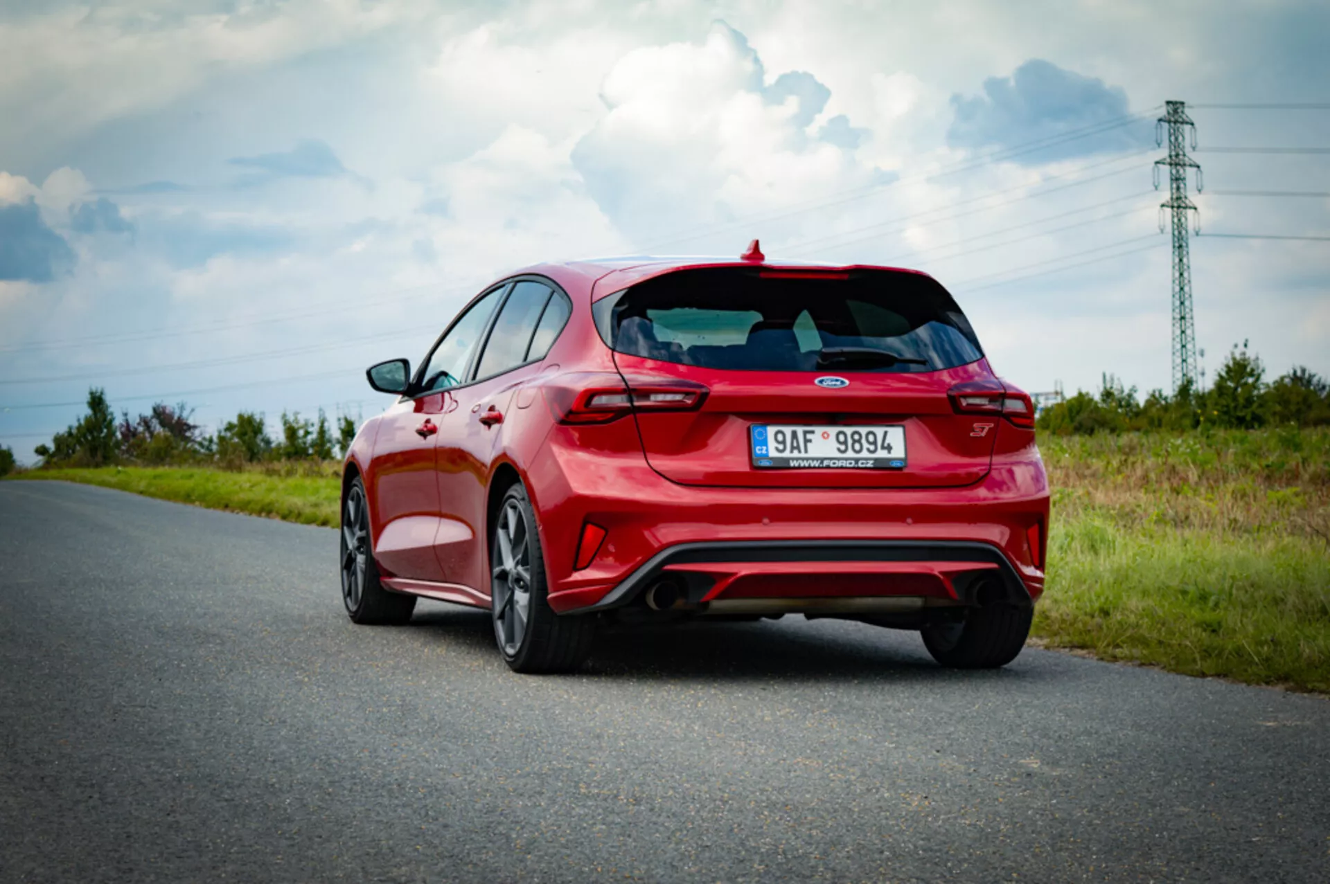 Vista trasera lateral de Ford Focus hatchback 2022 mostrando las luces traseras, ventana trasera, acabado deportivo con alerón y doble escape, capturada en un día soleado