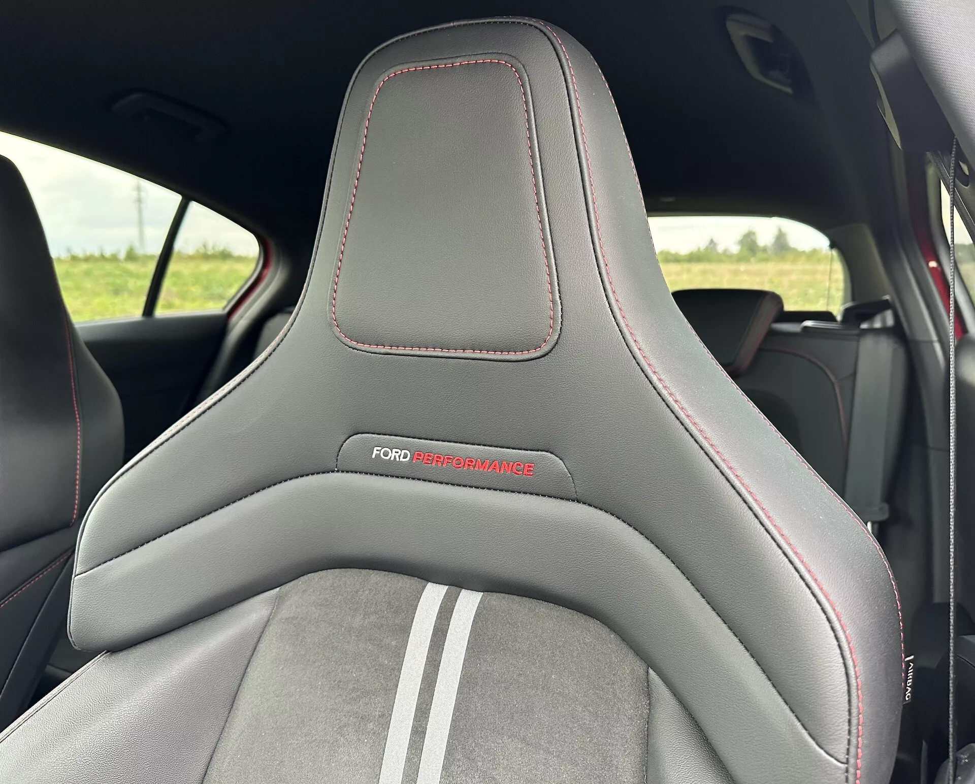 Vista detallada del asiento de un Ford Focus 2022 destacando su diseño deportivo con una combinación de materiales de cuero y ante, adornado con el logo de 'FORD PERFORMANCE' y detalles de costura roja.