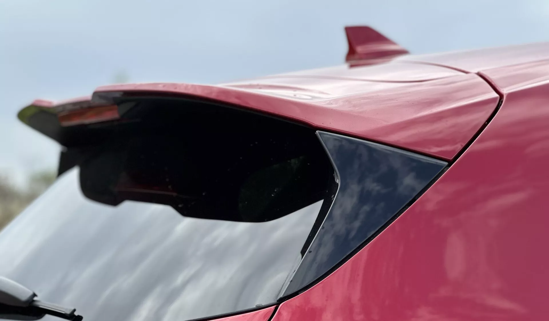 Primer plano del spoiler trasero de un Ford Focus 2022 en rojo, destacando su diseño aerodinámico y acabado brillante desde una perspectiva de ángulo bajo