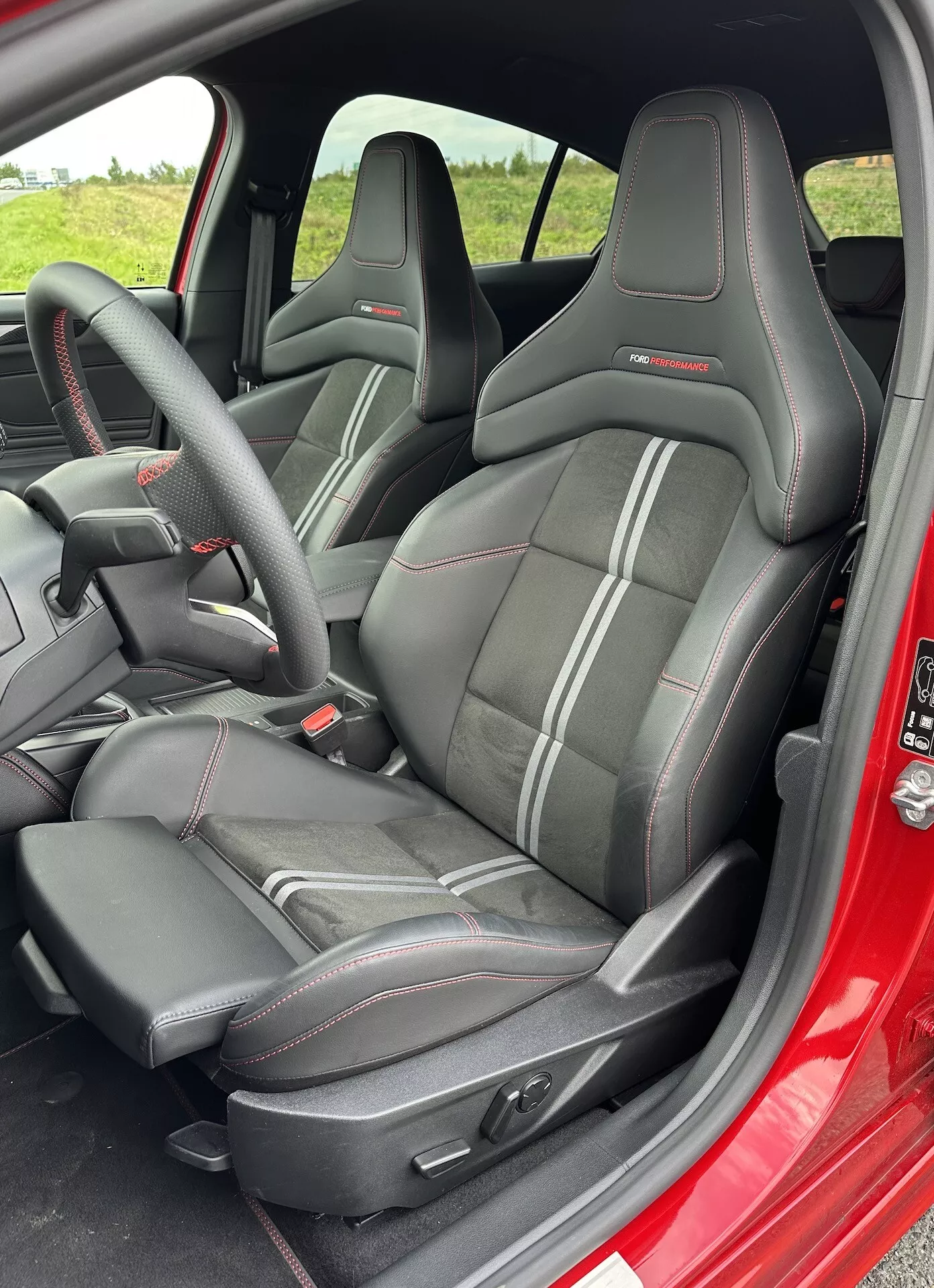 Interior de Ford Focus 2022 mostrando asientos tipo cubo de estilo deportivo con respaldo alto y reposacabezas integrados, tapicería negra con costuras en contraste y controles de ajuste de asiento electrónicos, desde la perspectiva de la puerta del lado del conductor