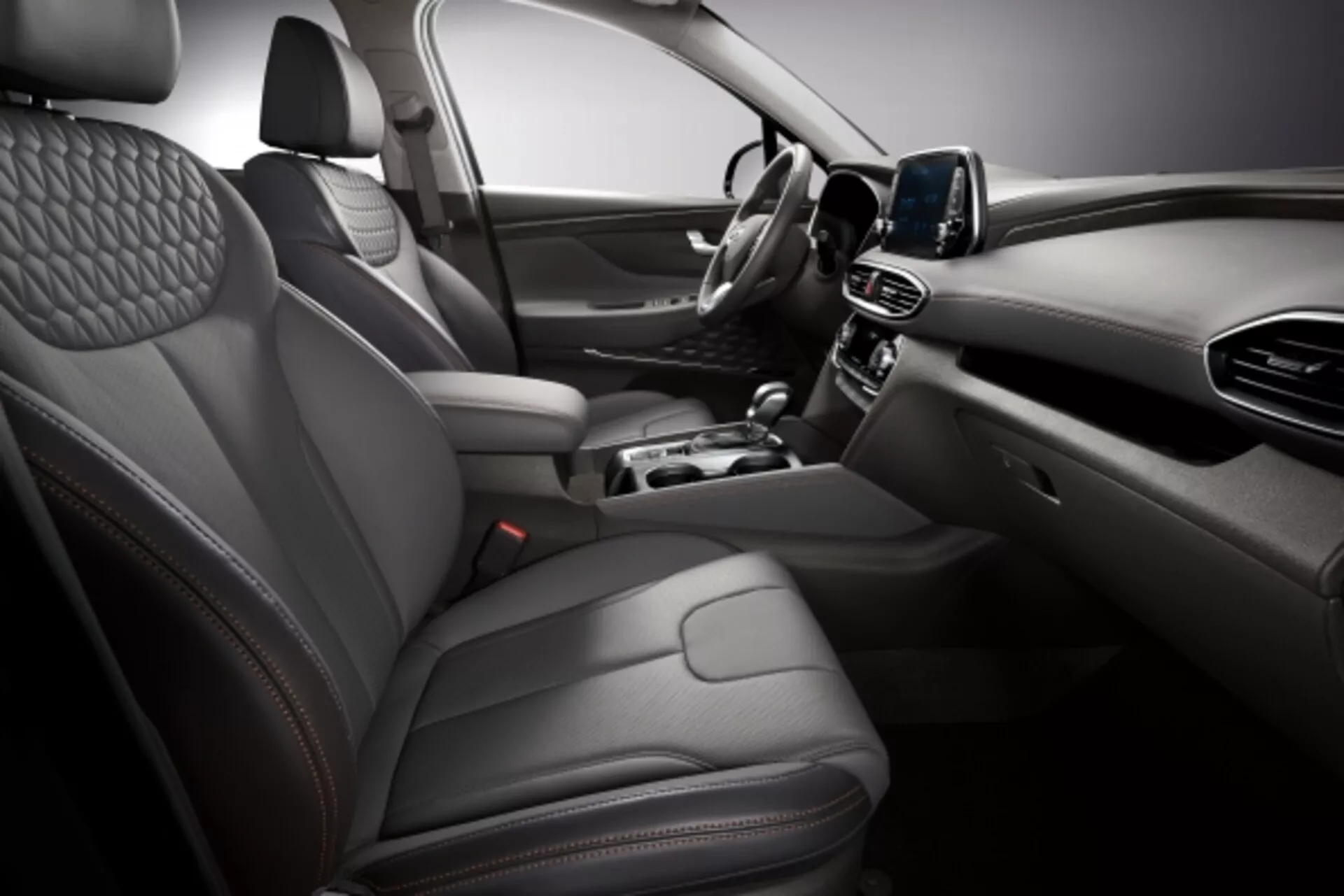 Foto interior del Hyundai Santa Fe 2015 mostrando asientos de cuero acolchado lujosos, tablero elegante con pantalla táctil y consola central moderna desde un ángulo elevado