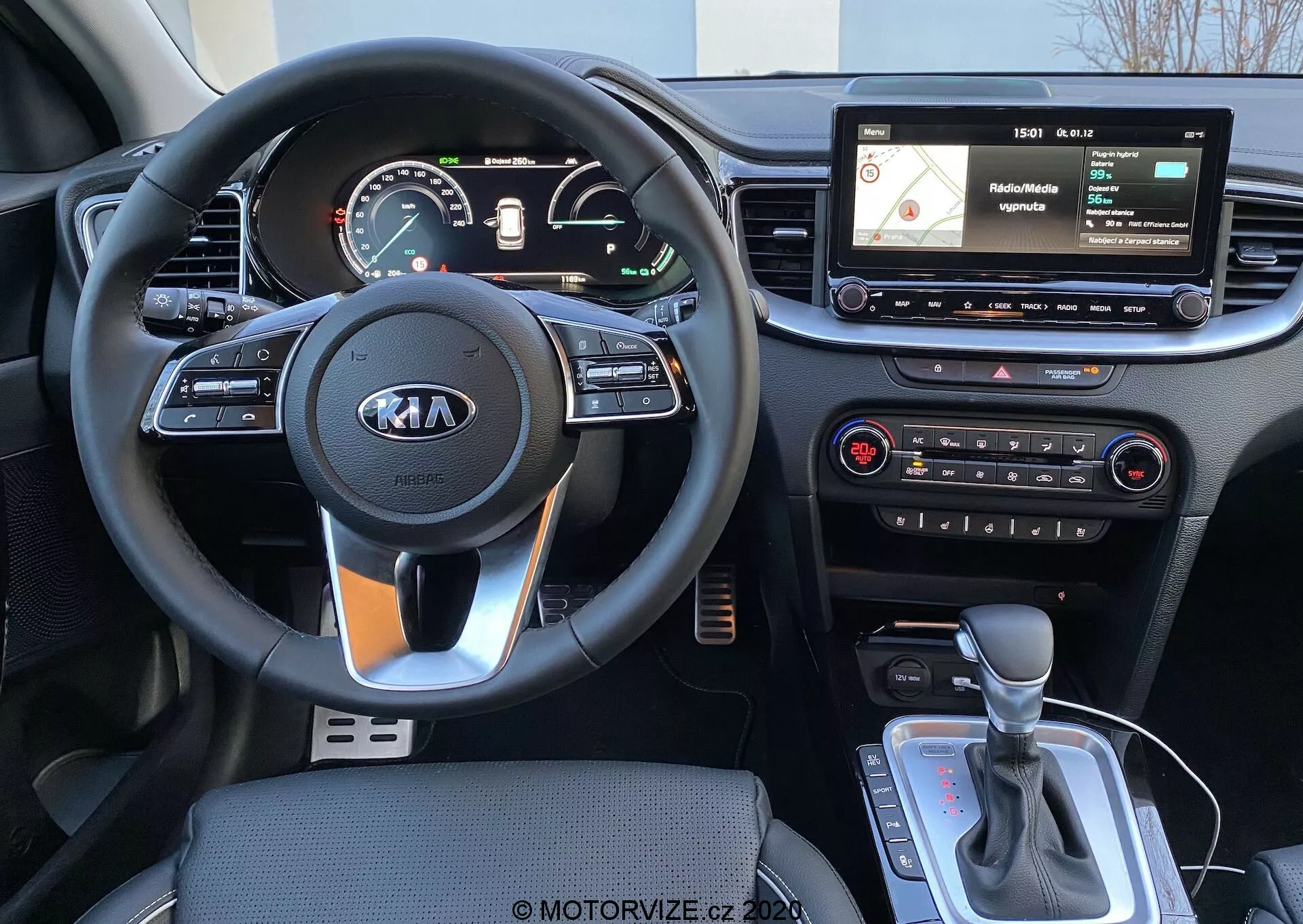 Vista interior de un Kia Ceed 2018 desde la perspectiva del conductor, que muestra un volante de tres radios con el logo de Kia, controles montados en el volante, un cuadro de instrumentos digital/analógico, una pantalla de infoentretenimiento flotante con navegación e interfaz de medios, controles físicos del sistema de climatización y una palanca de cambios automática con posible selector de modo de conducción o freno de mano electrónico.