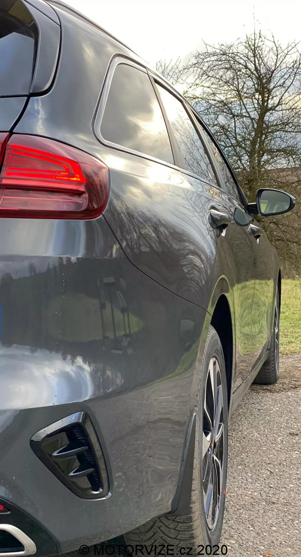 Primer plano de la vista lateral derecha de un SUV moderno desde una perspectiva ligeramente trasera que muestra la parte trasera y el perfil lateral desde la manija de la puerta trasera hasta las luces traseras, con líneas aerodinámicas suaves, pintura metálica oscura, grandes llantas de aleación, doble salida de escape, ventanas tintadas y una luz trasera de diseño contemporáneo.