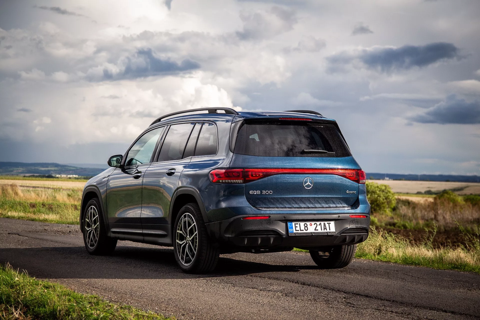 Mercedes-Benz EQB 2021 aparcado en carretera rural mostrando cuarto trasero y perfil lateral con luces traseras LED, baca y diseño elegante bajo iluminación natural
