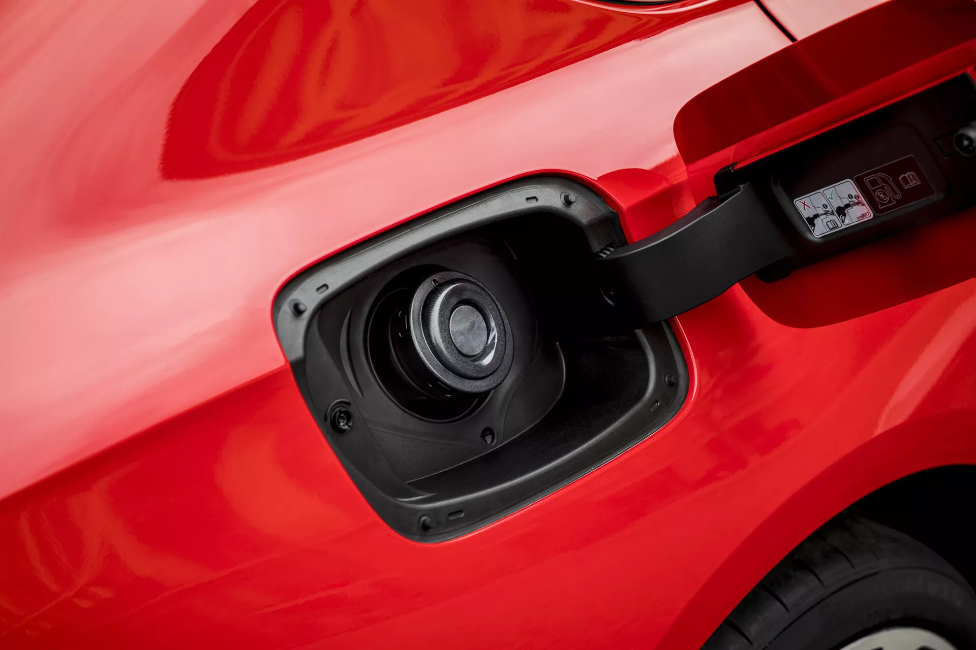 Primer plano del puerto de carga en un Opel Insignia 2013 que muestra su capacidad eléctrica o híbrida con una vista detallada de la puerta del puerto de carga abierta y el enchufe contra la carrocería roja del vehículo