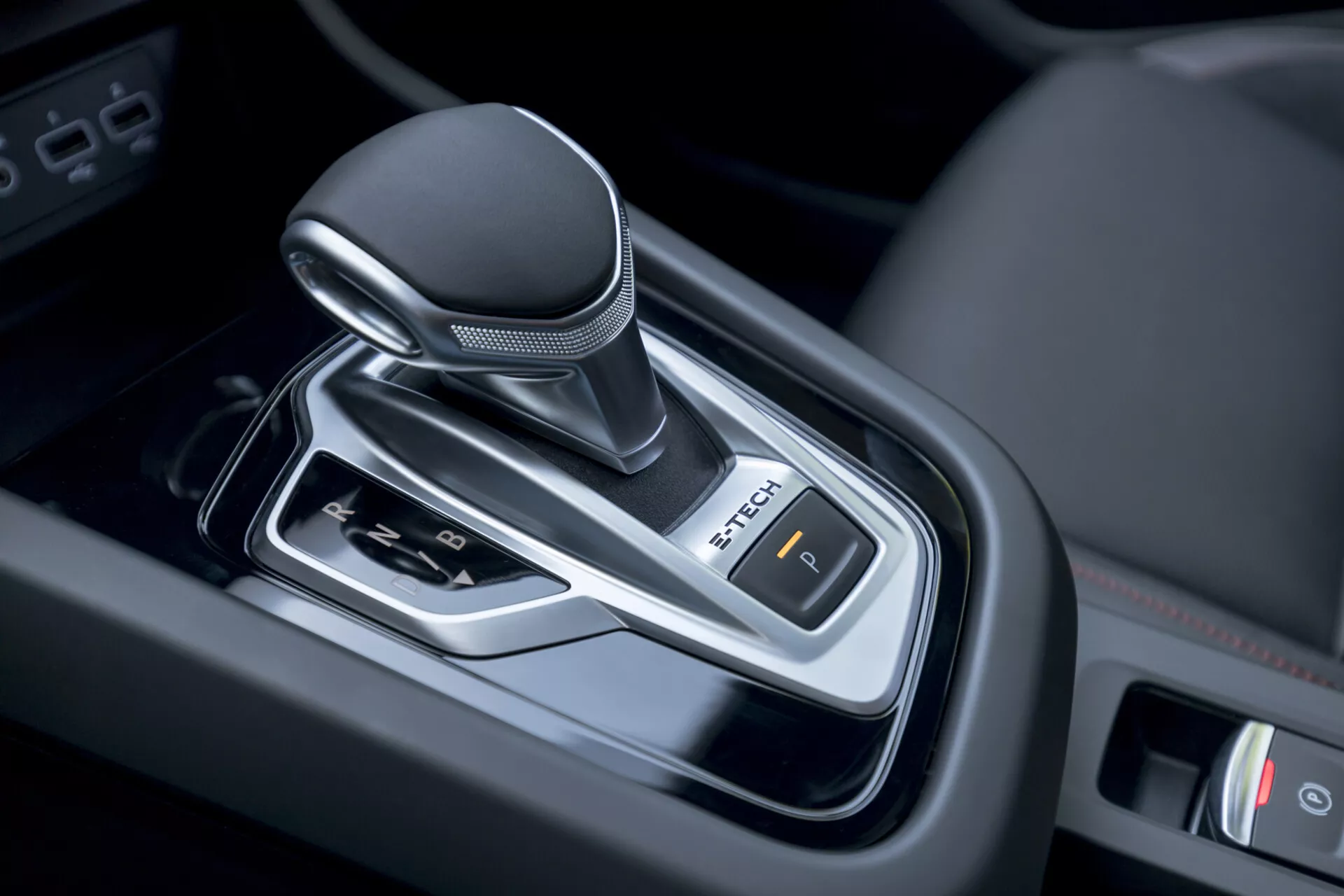 Vista detallada de la palanca de cambios de transmisión automática del Renault Arkana 2021 dentro del vehículo, mostrando un diseño moderno con pomo envuelto en cuero, acentos cromados y control de freno de estacionamiento electrónico.