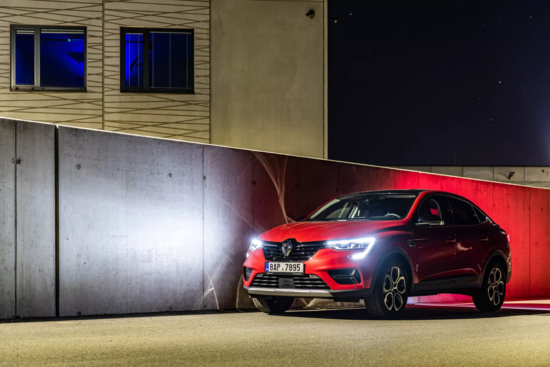 Hatchback deportivo Renault Arkana 2021 estacionado por la noche, mostrando faros LED, parrilla frontal y ruedas de aleación bajo iluminación artificial