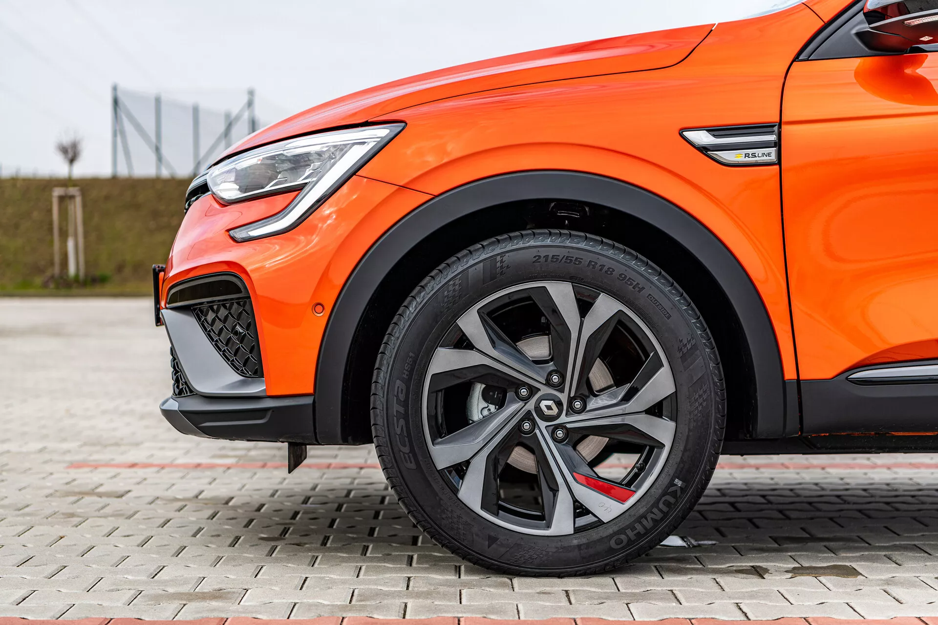 Vista lateral de cerca de un Renault Arkana 2021 naranja destacando las llantas de aleación de múltiples radios, neumáticos de bajo perfil, sistema de frenado de alto rendimiento y luz diurna LED
