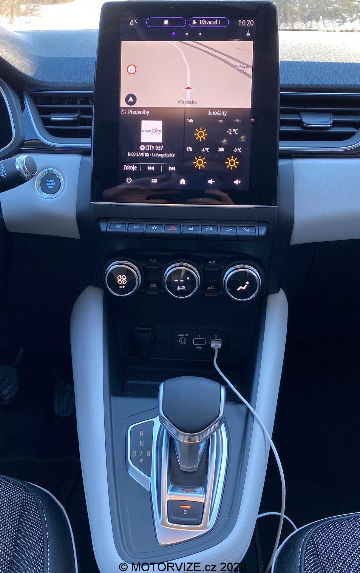 Interior del Renault Captur 2020 mostrando consola central y salpicadero con un gran sistema de infoentretenimiento táctil que muestra el mapa de navegación, controles de clima de doble zona, selector de marchas electrónico, portavasos, acentos de metal cepillado y posibles acabados de lujo.