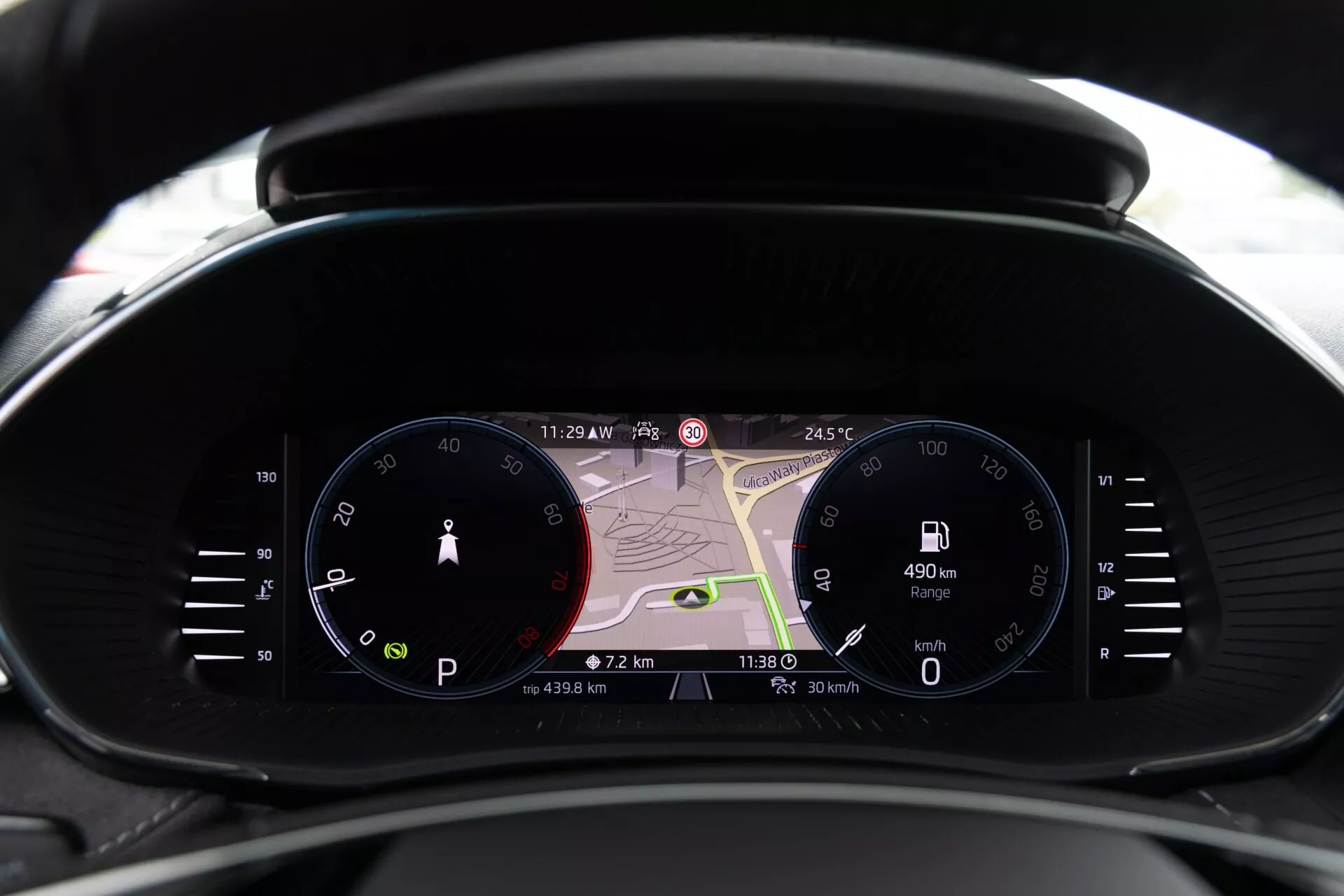 Vista de cerca del conjunto de instrumentos moderno del Skoda Fabia 2021 desde la perspectiva del conductor, con un velocímetro analógico, una gran pantalla digital con mapa de navegación y un cuentarrevoluciones digital. Las pantallas muestran 11:29 PM, 24.5°C, una autonomía de 490 km, velocidad actual de 0 km/h y datos de viaje. Combina diseño tradicional y contemporáneo con tecnología avanzada, incluyendo navegación en tiempo real, información del conductor e indicadores de conectividad.