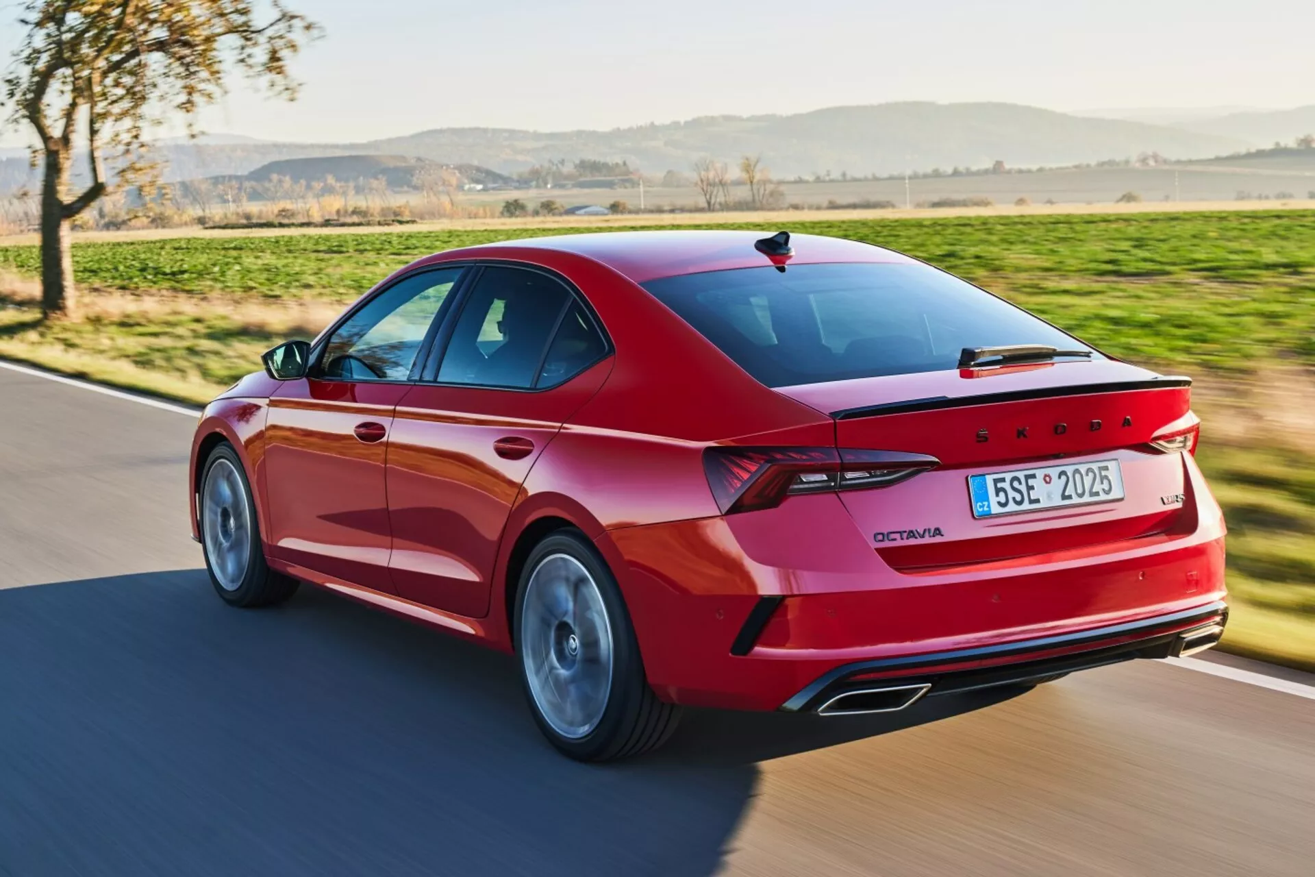 Vista trasera dinámica de tres cuartos de un Skoda Octavia Limusina del 2017 en rojo, mostrando su exterior deportivo con luces traseras LED, ruedas de aleación y características avanzadas bajo la luz natural del día