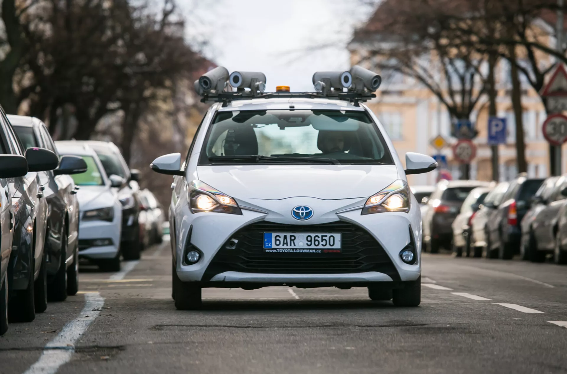 Hatchback Toyota 2017 equipado con sensores LiDAR y cámaras para tecnología de conducción autónoma, capturado desde una perspectiva frontal en una calle urbana