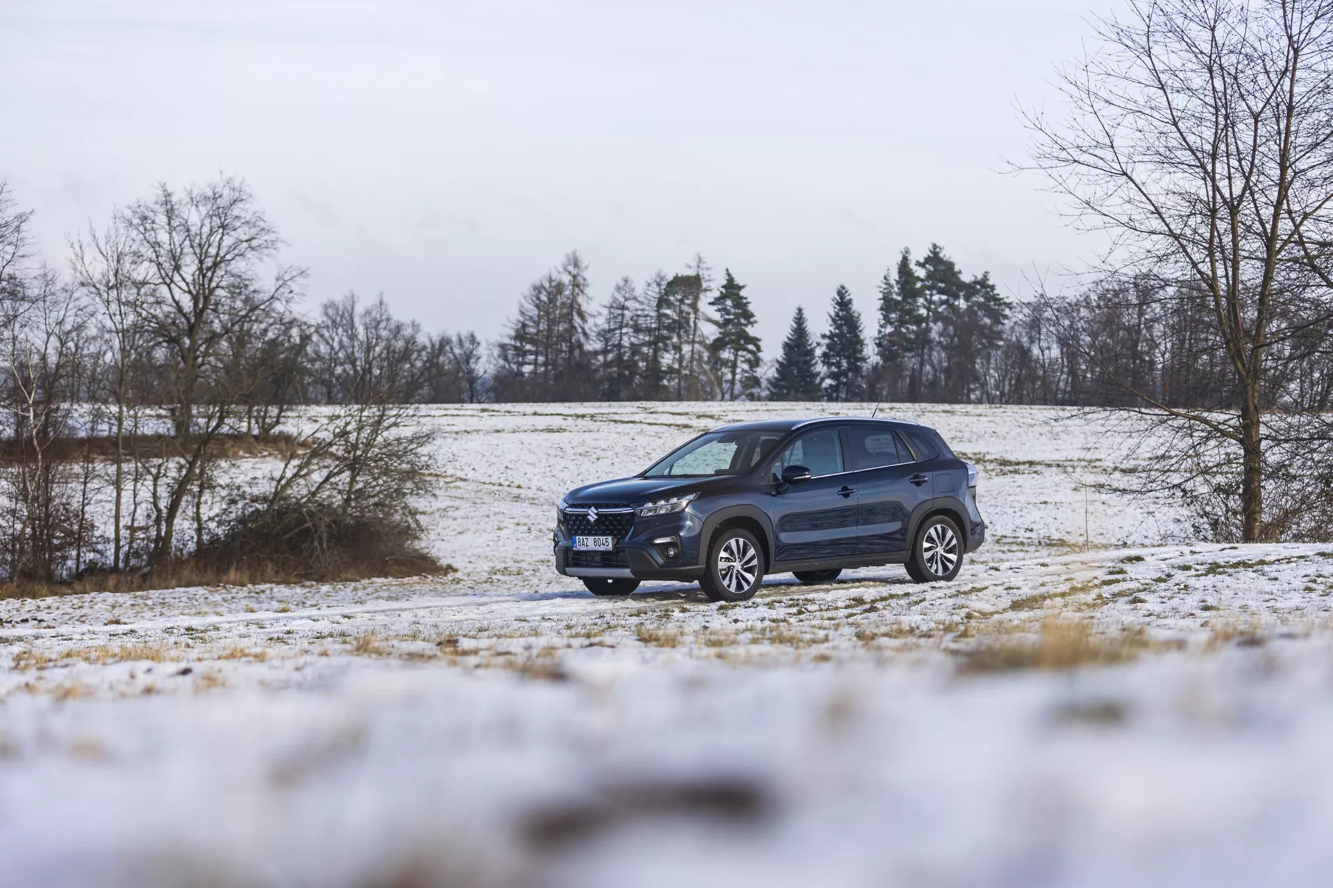 Suzuki S-Cross 2022 en un paisaje invernal con nieve, mostrando su diseño dinámico, iluminación avanzada, ruedas de aleación y barras en el techo, enfatizando su estilo SUV y capacidad todoterreno.