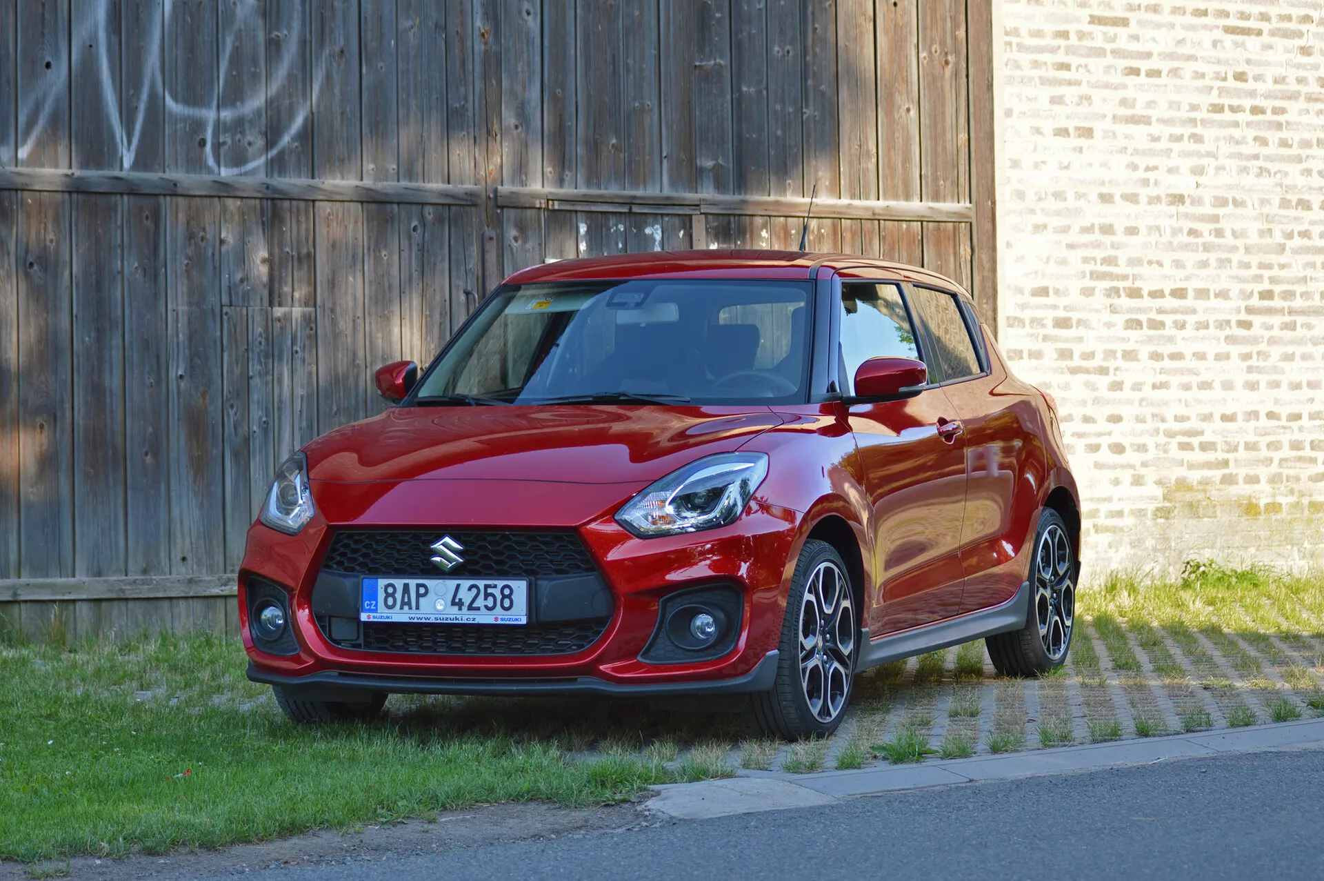 Suzuki Swift Sport 2017 en acabado rojo vibrante, vista de tres cuartos delantera, mostrando diseño deportivo, faros afilados, parrilla frontal agresiva, llantas de aleación y faldones laterales aerodinámicos