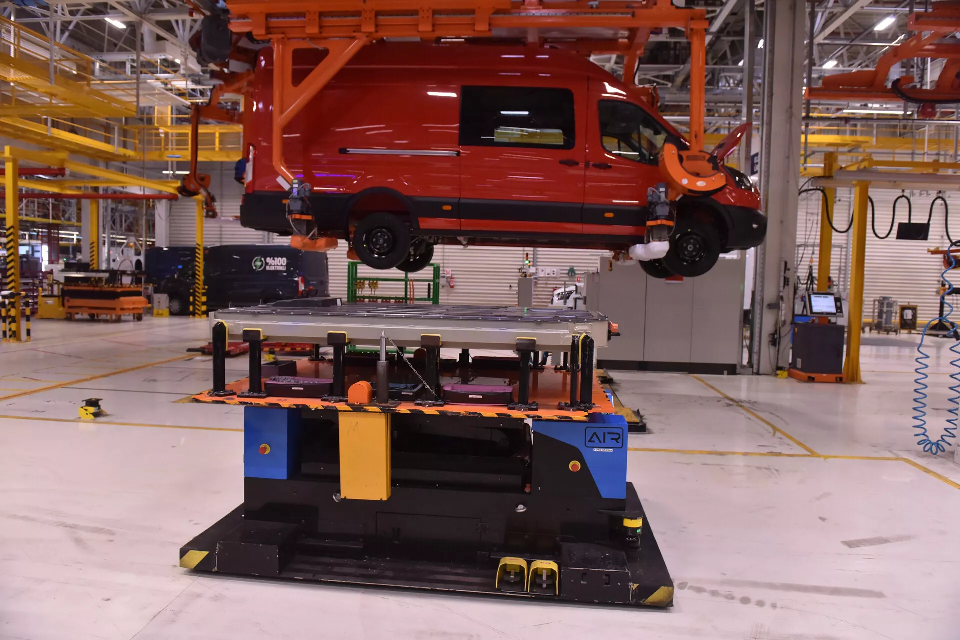 Furgoneta comercial Alfa-Romeo Stelvio 2017 suspendida por un sistema de manejo aéreo en una instalación de fabricación, mostrando tecnología en ensamblaje de vehículos y automatización de líneas de producción