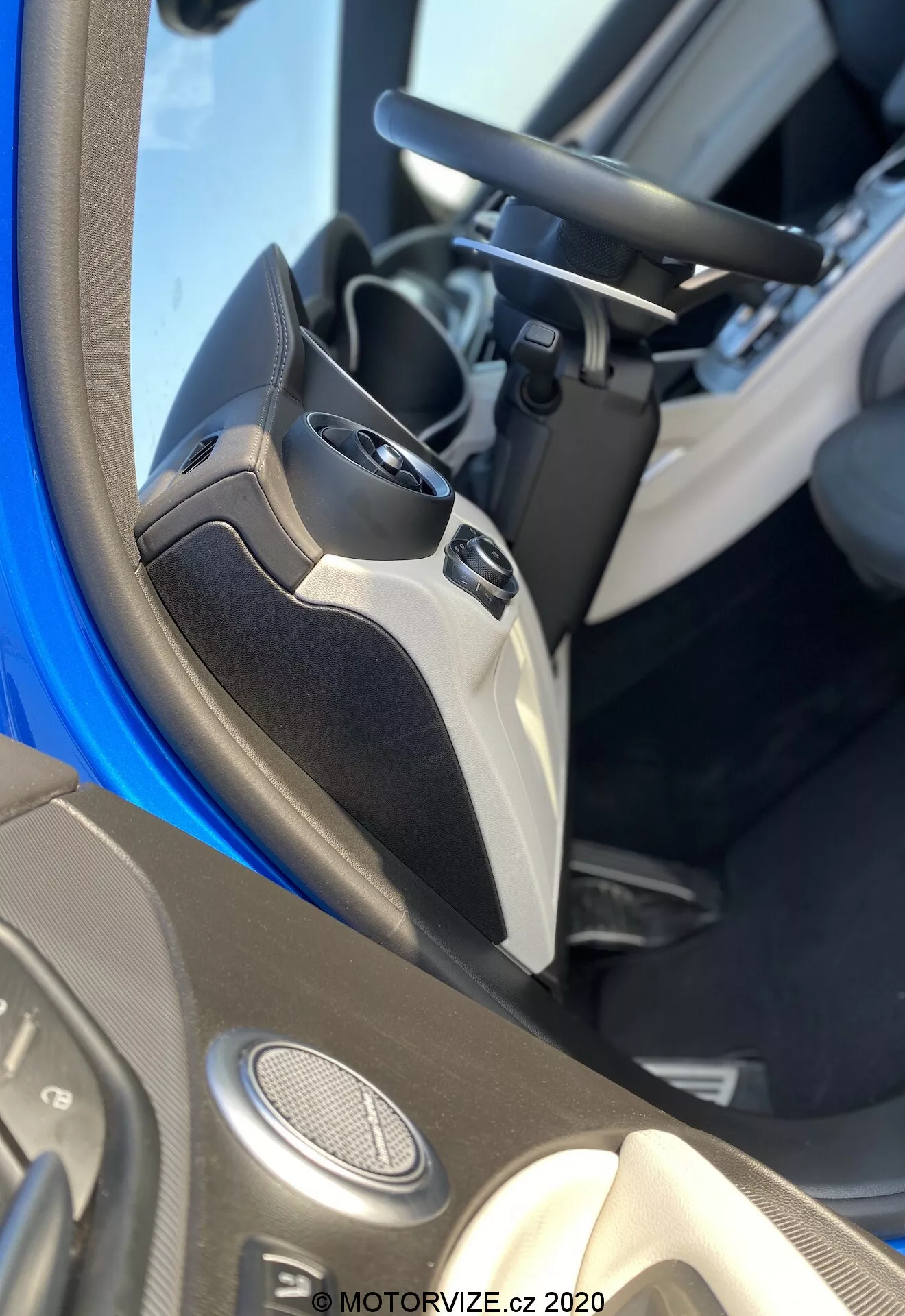 Primer plano del interior del Alfa Romeo Stelvio 2017 enfocado en el panel de la puerta del conductor. La toma captura la mitad inferior de la puerta y parte del asiento del conductor, mostrando varias características tecnológicas. El panel incluye altavoces montados en la puerta que sugieren un sistema de audio avanzado, controles de ventanas eléctricas con varios botones para función de un toque, y un control de ajuste del espejo lateral eléctrico. También es visible la manija de la puerta, integrada en el diseño. Los materiales utilizados implican un nivel de acabado específico o un paquete de interior, con un bolsillo de almacenamiento en la parte inferior. La imagen está marcada con 'MOTORVIZE.cz 2020'.
