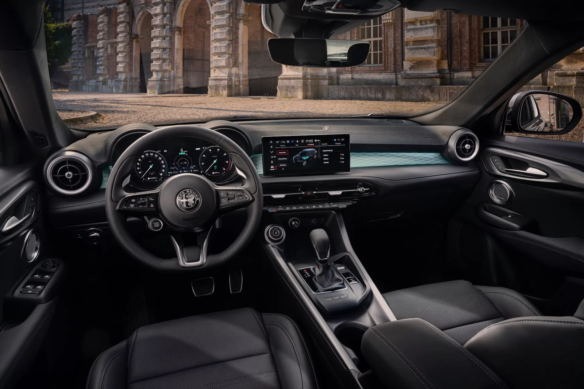 Vista interior del Alfa Romeo Tonale 2022 desde el asiento trasero del pasajero mostrando la cabina, volante con controles, tablero digital, pantalla horizontal de infotainment, consola central con palanca de cambios y asientos de cuero de lujo