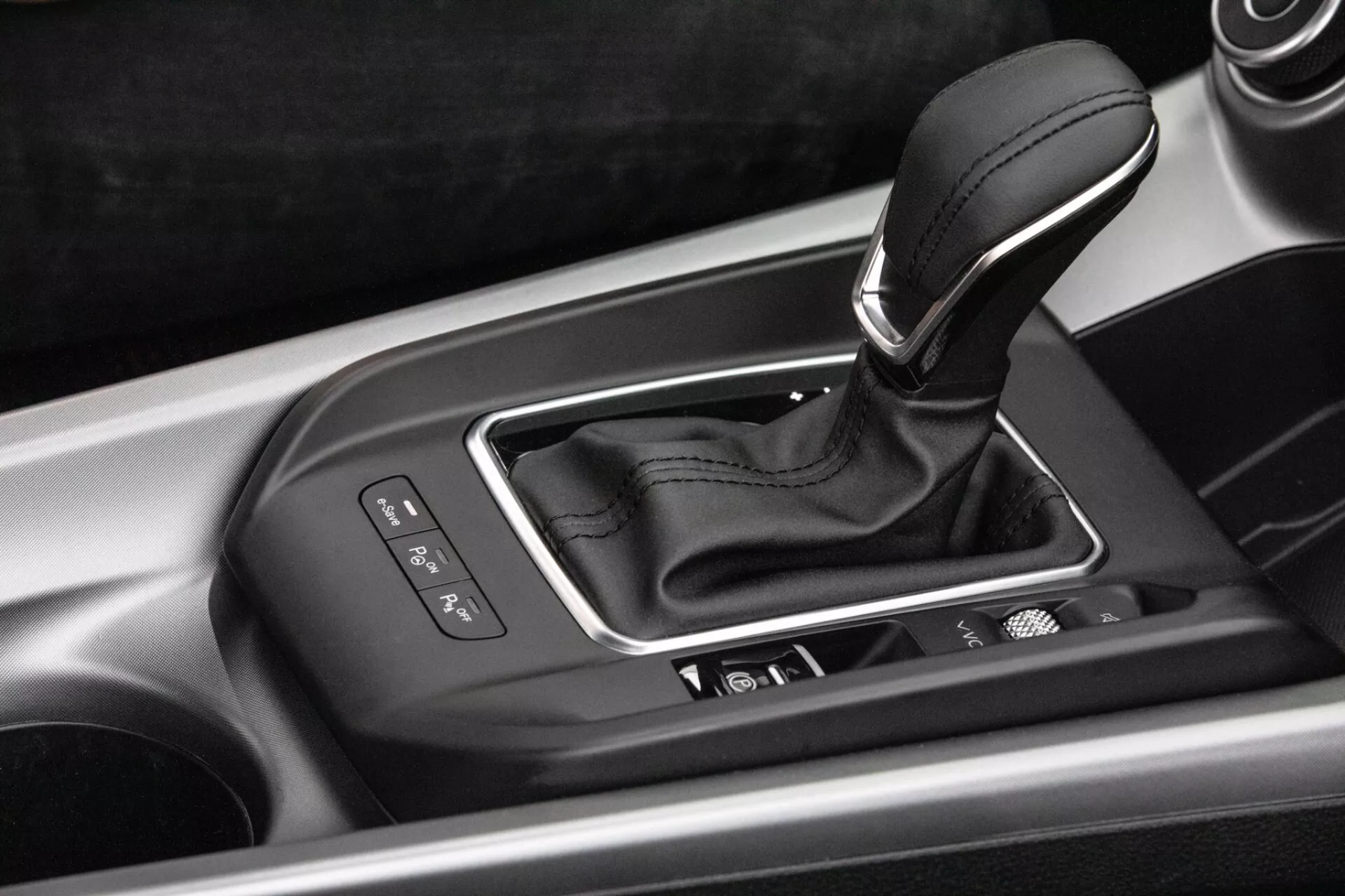 Vista interior detallada de la consola central del Alfa-Romeo Tonale 2022 con palanca de cambio de transmisión automática en carcasa plateada con indicadores de selección de marcha, botones de control integrados y acabado de alta calidad