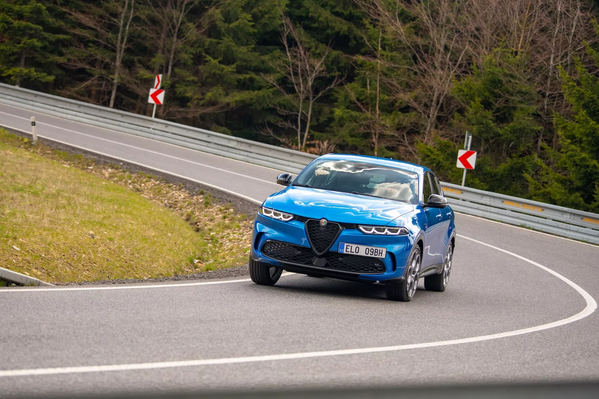 Conducción dinámica del Alfa Romeo Tonale 2022 en carretera curva mostrando vista de cuarto delantero, faros LED, parrilla distintiva y ruedas de alto rendimiento