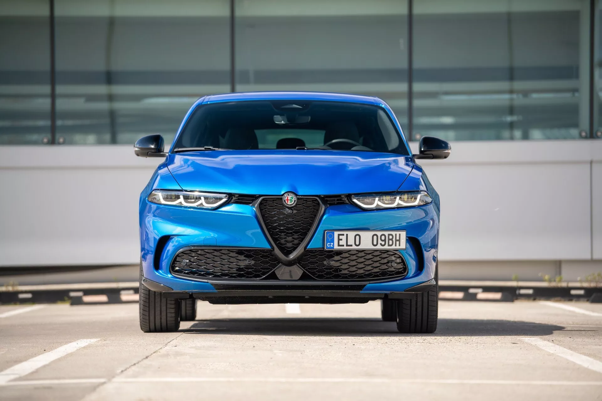 Alfa Romeo Tonale 2022 en azul, vista frontal en estacionamiento destacando parrilla con emblema, faros LED y características de diseño aerodinámico