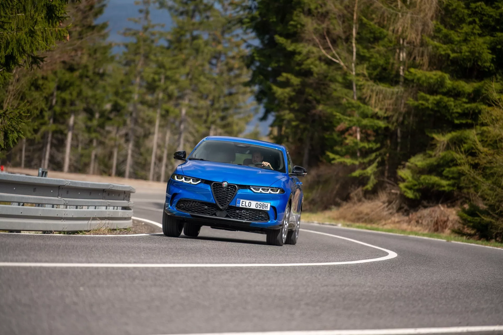 Alfa-Romeo Tonale 2022 en movimiento en una carretera curva, mostrando su diseño dinámico, faros LED, tomas de aire, estilo convertible deportivo y características de lujo desde una perspectiva frontal de tres cuartos en ángulo bajo
