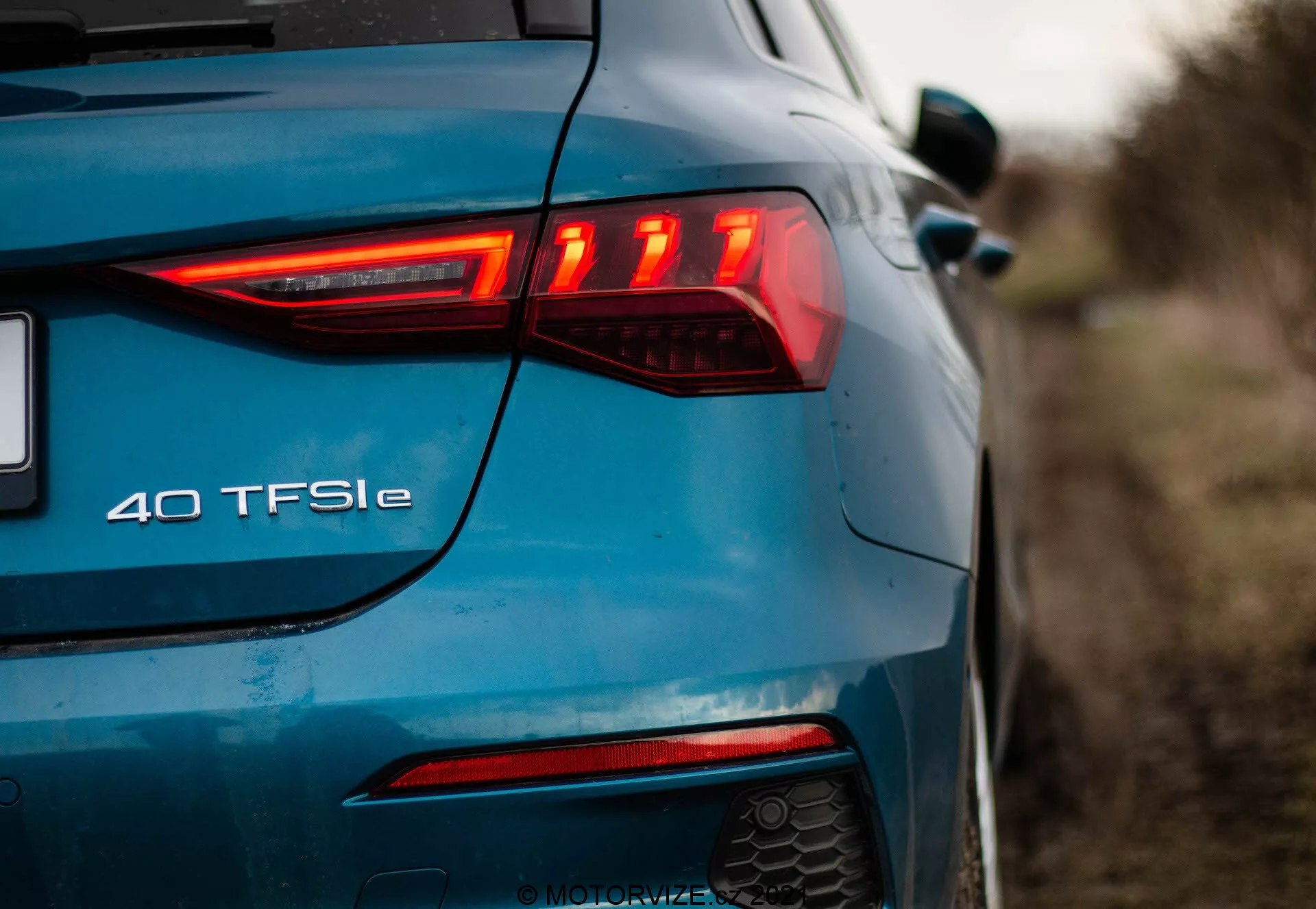 Ángulo trasero-izquierdo del Audi A3 2020 Sportback azul, destacando el diseño moderno de la luz trasera LED con elementos horizontales, luz antiniebla trasera, sistema de escape doble y la insignia '40 TFSI e' que indica un tren motriz híbrido eléctrico.