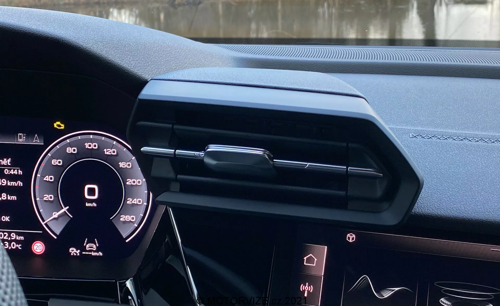 Vista interior del Audi A3 Sportback 2020 desde el asiento del conductor, mostrando el cuadro de instrumentos digital, un diseño de tablero elegante con ventilación central cerrada y moldura decorativa, borde de la pantalla de infotainment, materiales de alta gama de cuero con costuras, iluminación ambiental y volante parcialmente visible con posibles controles, destacando la tecnología automotriz moderna y el diseño de lujo.