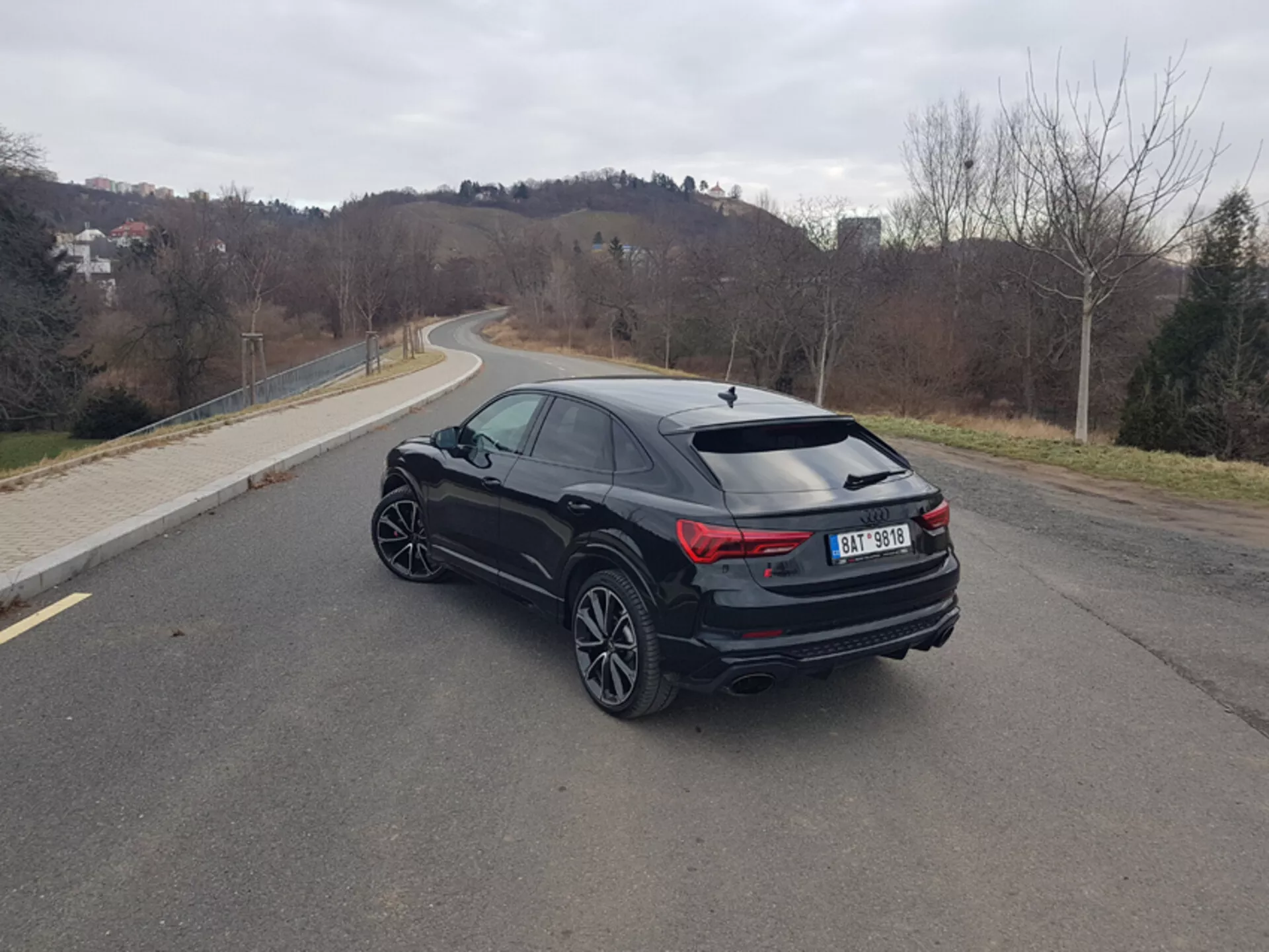 Audi Q3 RS 2015, vista trasera en ángulo de tres cuartos en carretera de asfalto, destacando luces traseras LED elegantes, escape de rendimiento y llantas de aleación deportivas