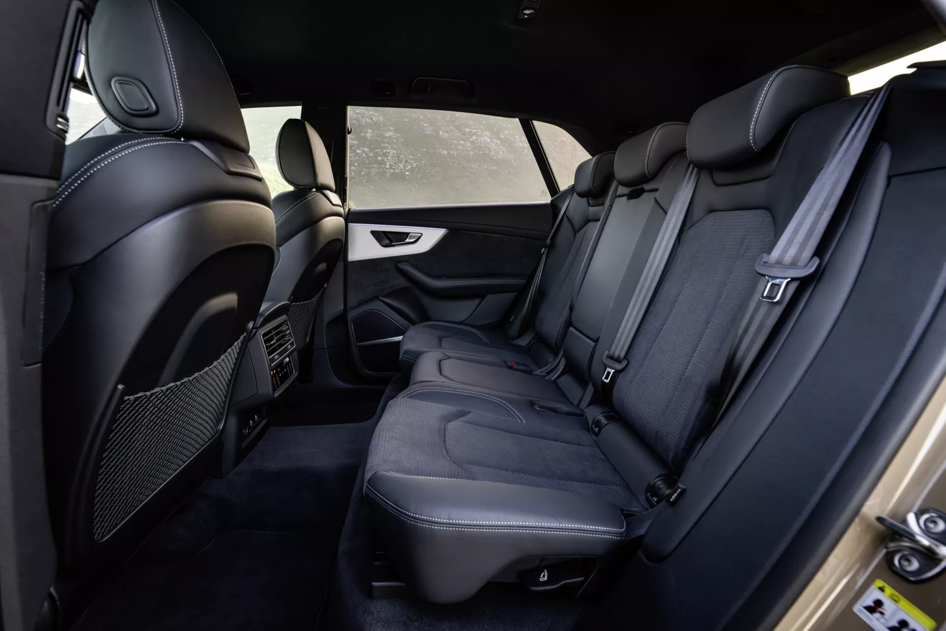 Interior del Audi Q8 4M-Facelift 2023 mostrando el compartimento trasero de pasajeros desde el lado del conductor con asientos de cuero negro de primera calidad, costuras detalladas, comodidades de lujo y características de seguridad