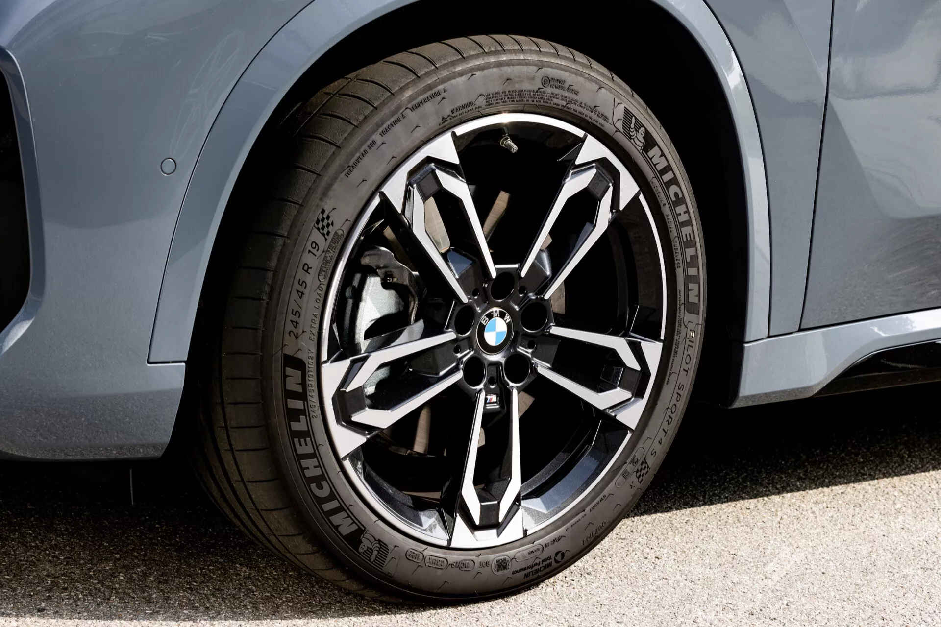 Vista de cerca de la rueda delantera y sección lateral del BMW X1 2022 (U11), destacando una rueda de aleación de múltiples radios con logo de BMW, neumáticos de rendimiento Michelin y acabado de pintura metálica