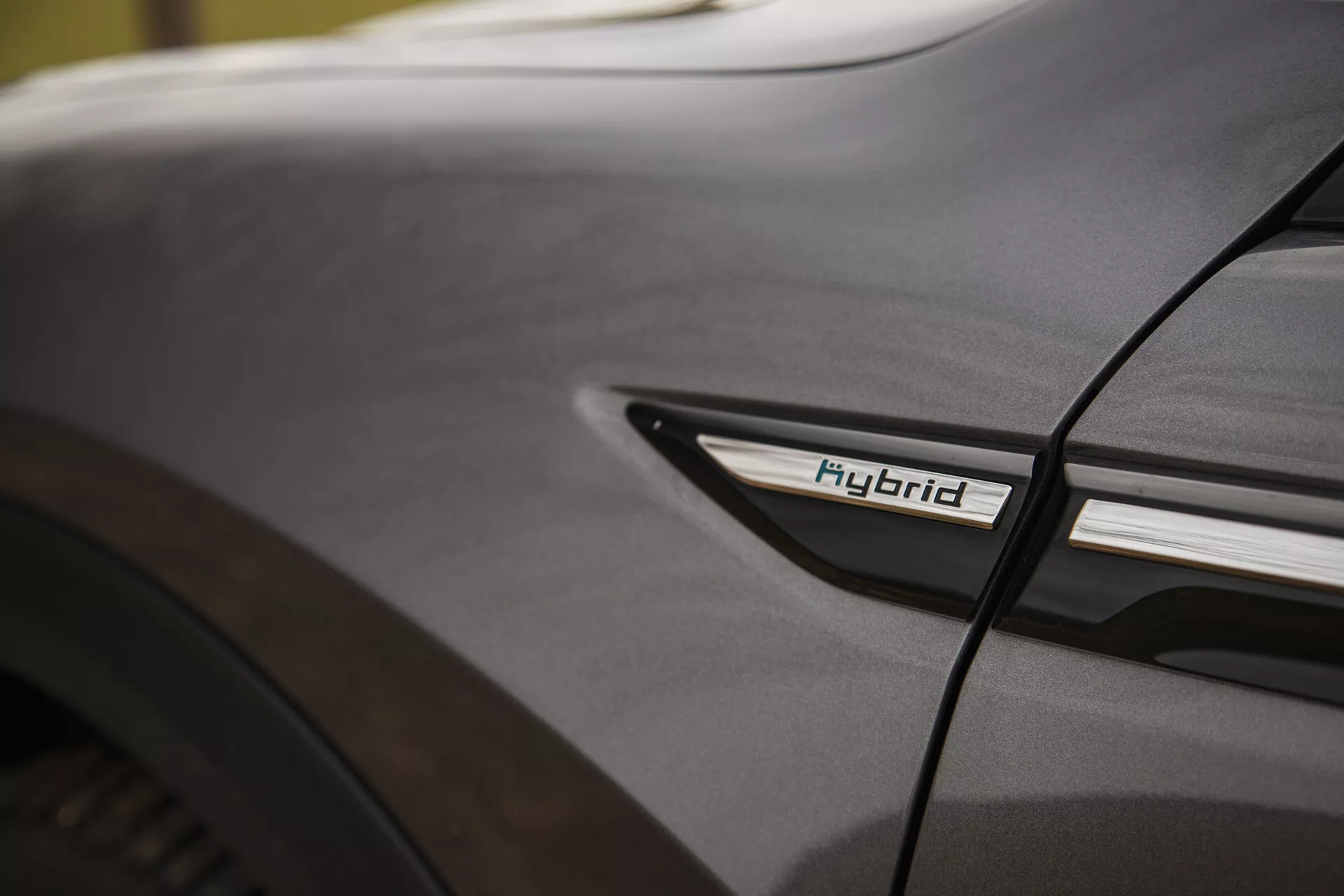 Detalle cercano del Citroen C5-X 2022 mostrando el emblema Híbrido en el perfil lateral bajo cerca del paso de rueda trasero, destacando la tecnología híbrida y la estética de diseño bajo condiciones de iluminación suave