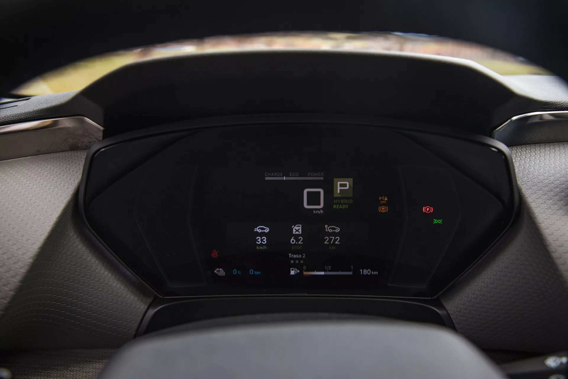 Vista cercana del tablero digital de un Citroen C5-X 2022 mostrando métricas del vehículo, incluido el indicador de marcha, velocímetro y consumo de energía, con un volante y parabrisas desenfocados en primer plano y fondo respectivamente.