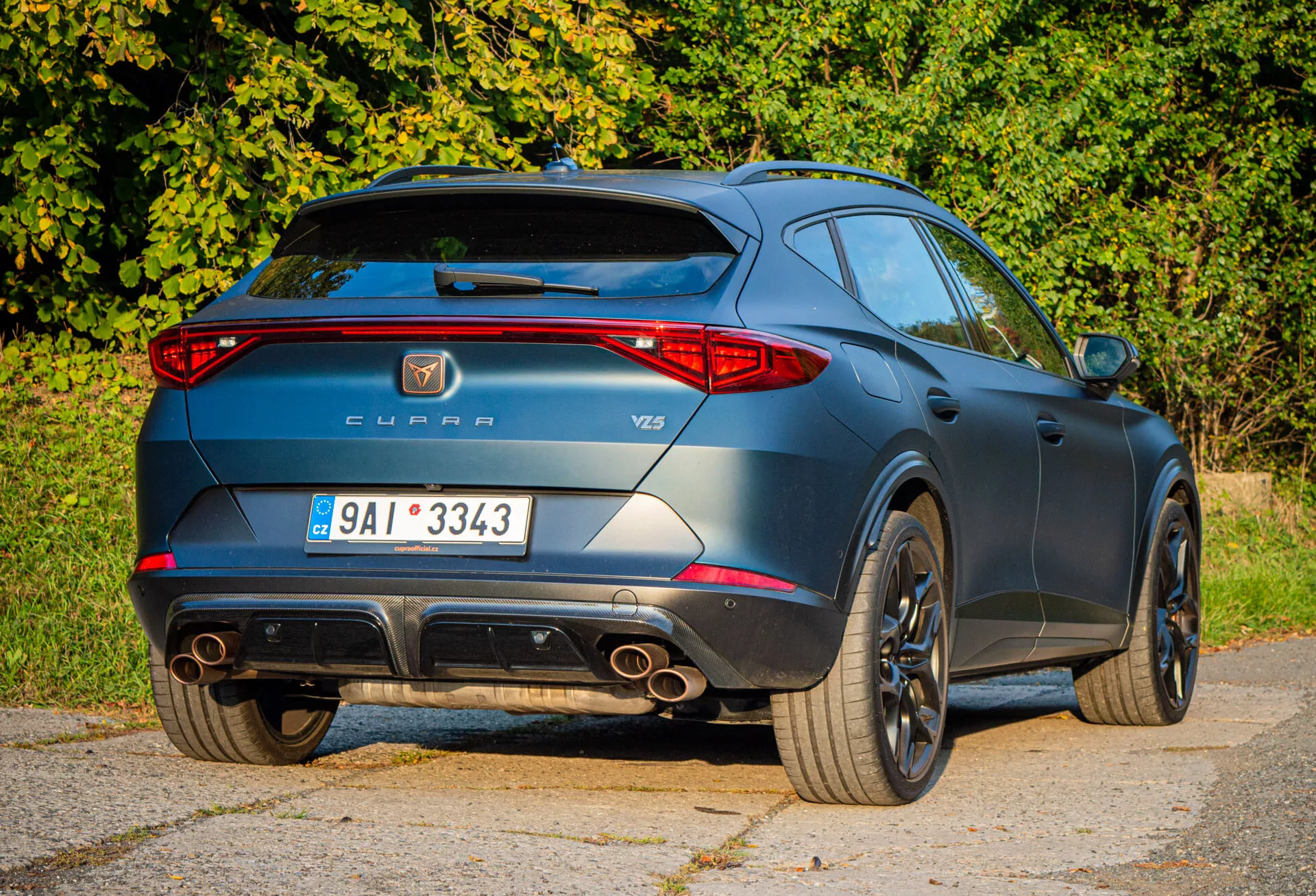 Vista trasera tres cuartos del Cupra Formentor 2020 resaltando características deportivas como puntas de escape dobles, alerón de techo y ruedas de aleación, junto con la insignia del fabricante y modelo durante el día