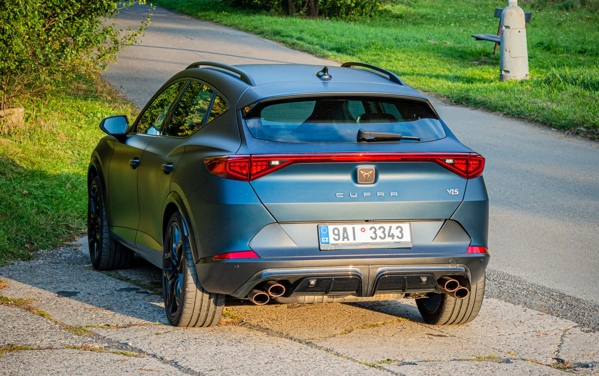 Vista trasera de un SUV Cupra Formentor VZ5 2020 con luces traseras LED, sistema de escape cuádruple, difusor y parachoques trasero deportivo, ruedas de múltiples radios y acabado mate antracita, fotografiado en un entorno suburbano durante el día