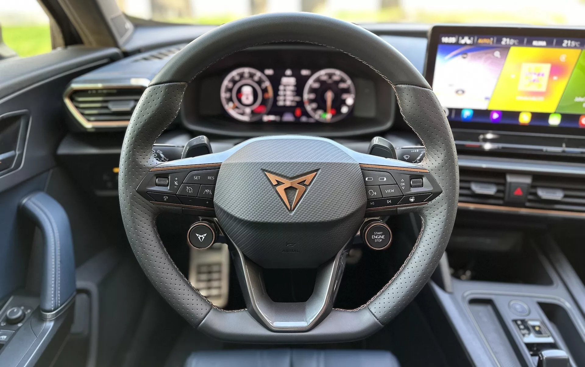 Vista interior de un Cupra Formentor 2020 desde la perspectiva del asiento del conductor, destacando el volante de tres radios forrado en cuero con botones multifunción, un cuadro de instrumentos digital y sistema de infoentretenimiento táctil.