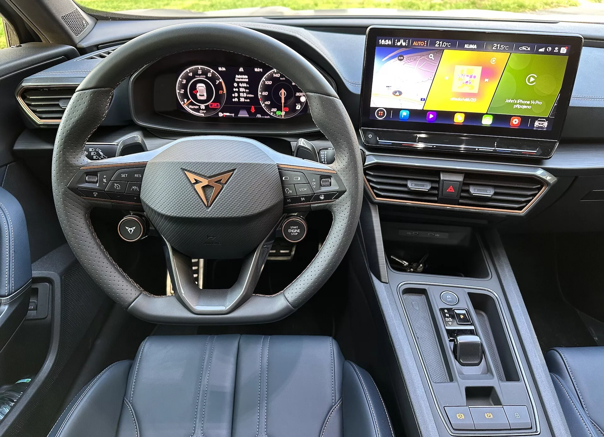Vista interior del Cupra Formentor 2020 desde la perspectiva del conductor mostrando volante multifunción forrado en cuero con logo de la marca del coche, cuadro de instrumentos digital, sistema de infoentretenimiento táctil, materiales del tablero de alta calidad con costuras de acento, selector de marchas automático y características de alta tecnología bajo luz natural