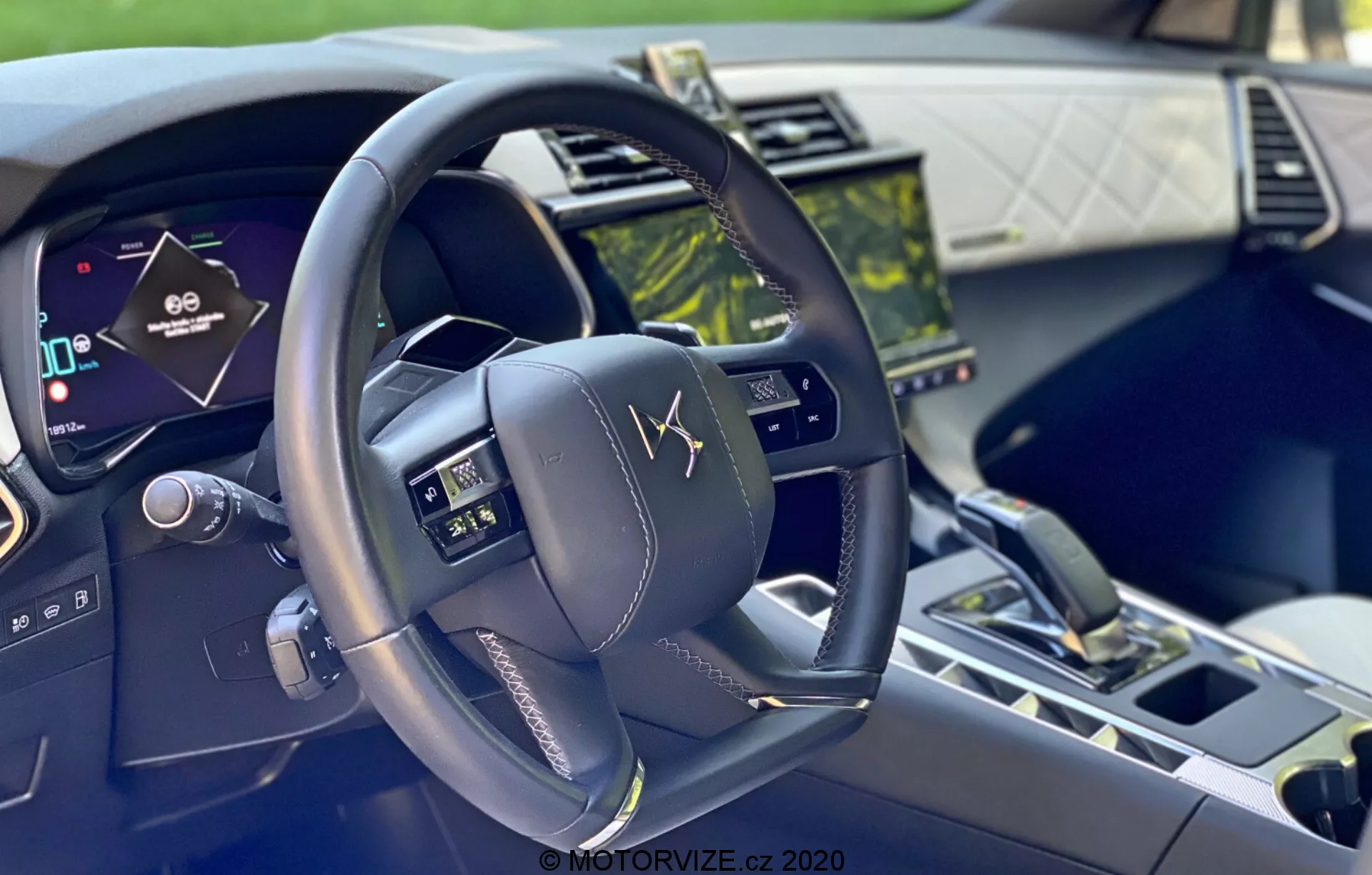 Toma interior del DS-7 Crossback 2018 desde la perspectiva del conductor, mostrando un volante multifuncional moderno con botones de control, un cuadro de instrumentos digital y un sistema de infoentretenimiento de pantalla táctil, destacando la tecnología avanzada y los materiales de lujo.