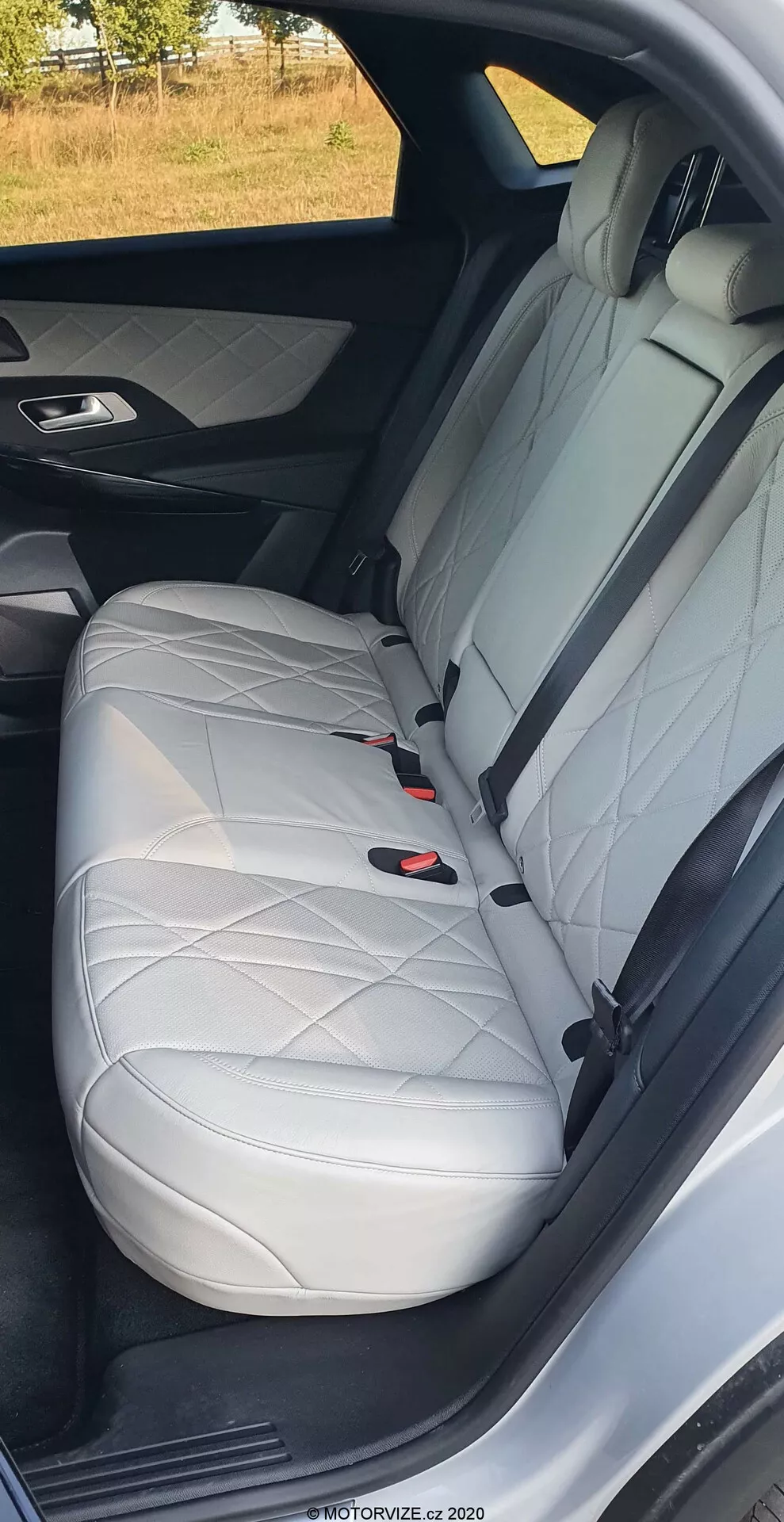 Primer plano del asiento trasero del DS Automobiles DS-7 2018, mostrando cuero blanco con costuras en forma de diamante, reposacabezas, cinturón de seguridad de tres puntos y sistema LATCH, destacando el diseño lujoso del interior y las características de seguridad del coche