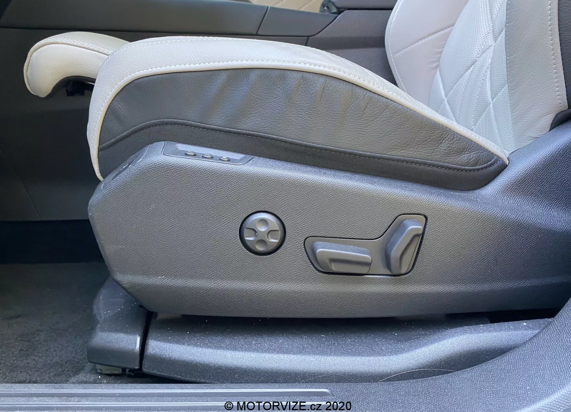 Primer plano del panel de ajuste del asiento delantero del conductor en un DS Automobiles DS 7 Crossback 2018. La imagen captura los controles de ajuste del asiento operados eléctricamente, incluidos los botones para la ajustabilidad multi-nivel y un dial redondo para configuraciones de memoria. El asiento presenta una tapicería en dos tonos, gris claro y oscuro, mostrando un diseño moderno y ergonómico característico de los interiores de automóviles de lujo.