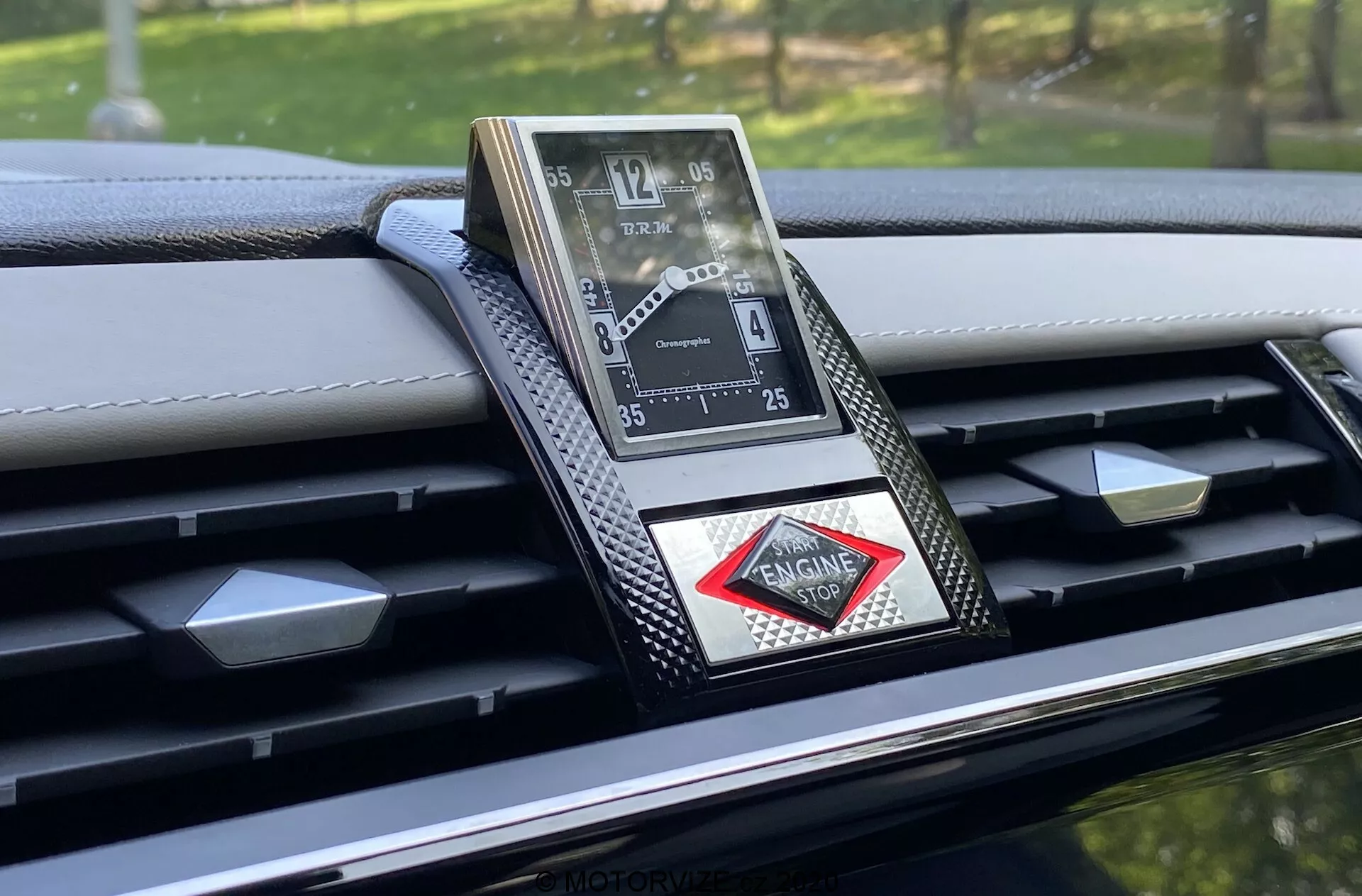 Toma de primer plano del reloj analógico lujoso incrustado en el tablero del DS-7 Crossback 2018, mostrando un diseño sofisticado con números romanos, acabado metálico y logotipo en forma de diamante. El tablero presenta acentos de fibra de carbono y detalles de costura, enfatizando la artesanía de alta gama y los materiales avanzados en este interior de automóvil premium.